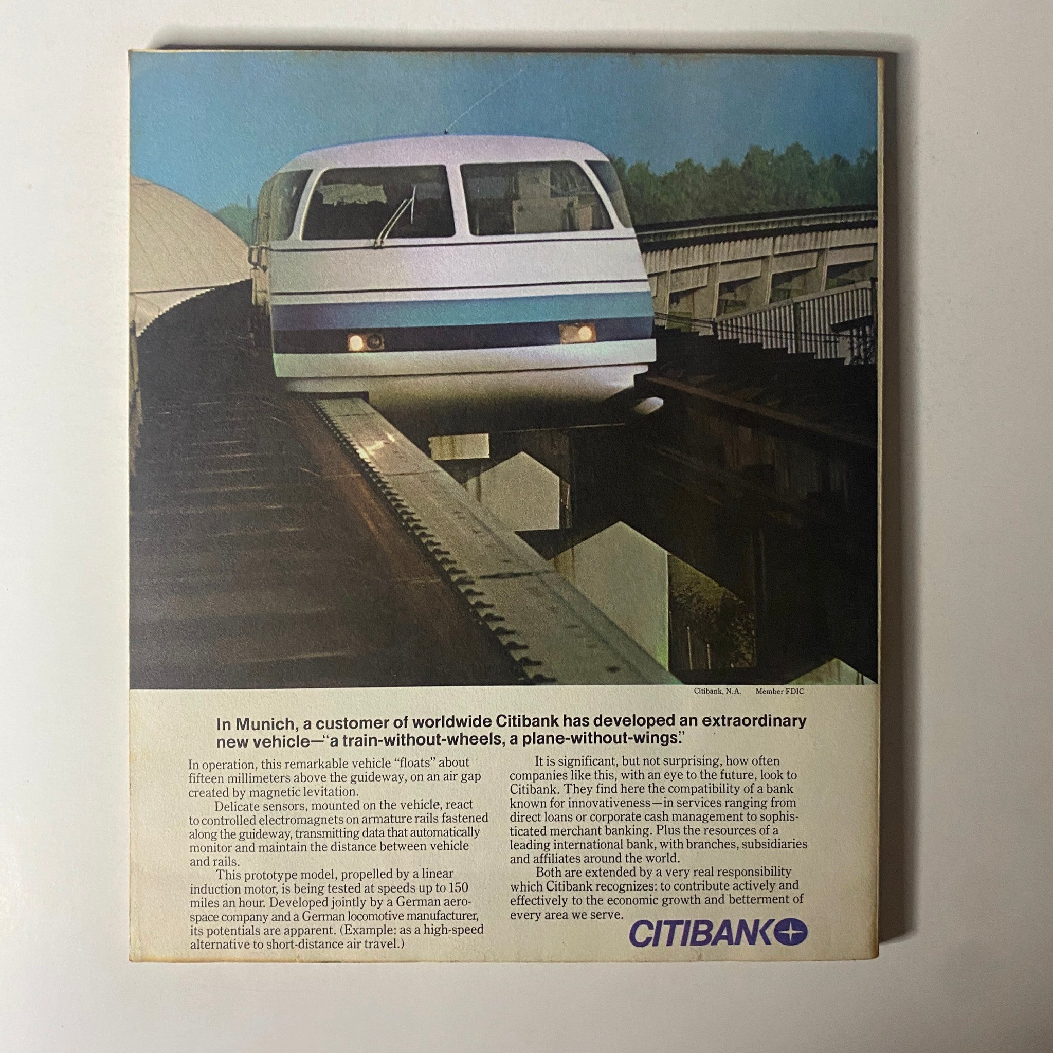 The back cover of Fortune Magazine March 1977 showcasing an innovative vehicle developed by Citibank, described as 'a train-without-wheels, a plane-without-wings.' The image depicts the futuristic design of the vehicle above a guideway.