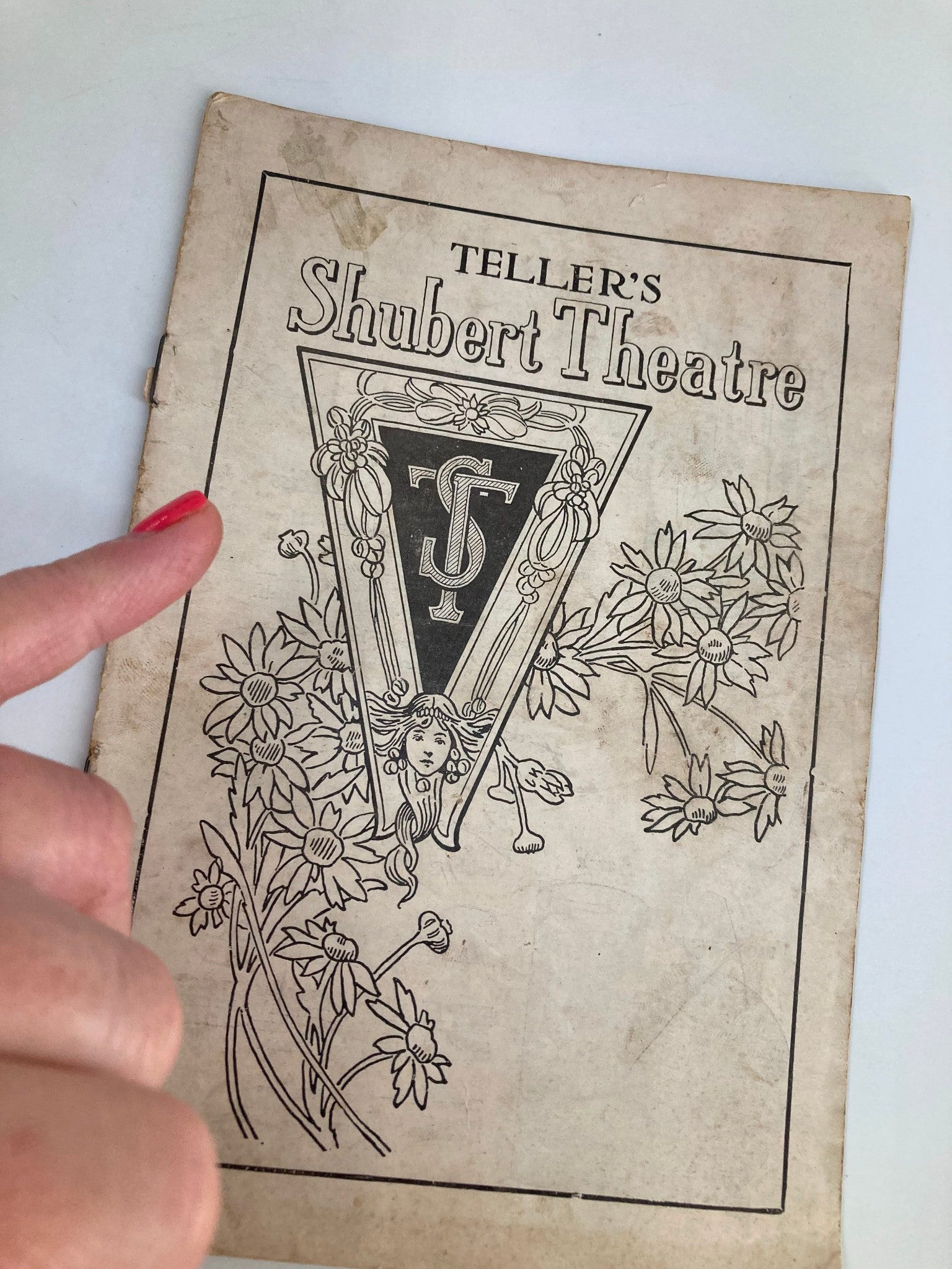 Close-up of the cover of the 1922 Teller's Shubert Theatre Musical Play Marjolaine, showing floral designs and a hand pointing to the title.
