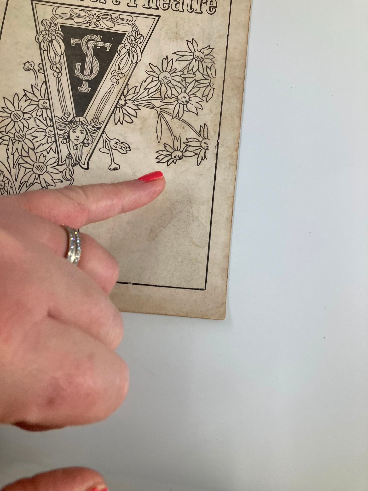 Detail of the 1922 Teller's Shubert Theatre Musical Play Marjolaine cover, highlighting floral designs with a hand pointing to the logo.