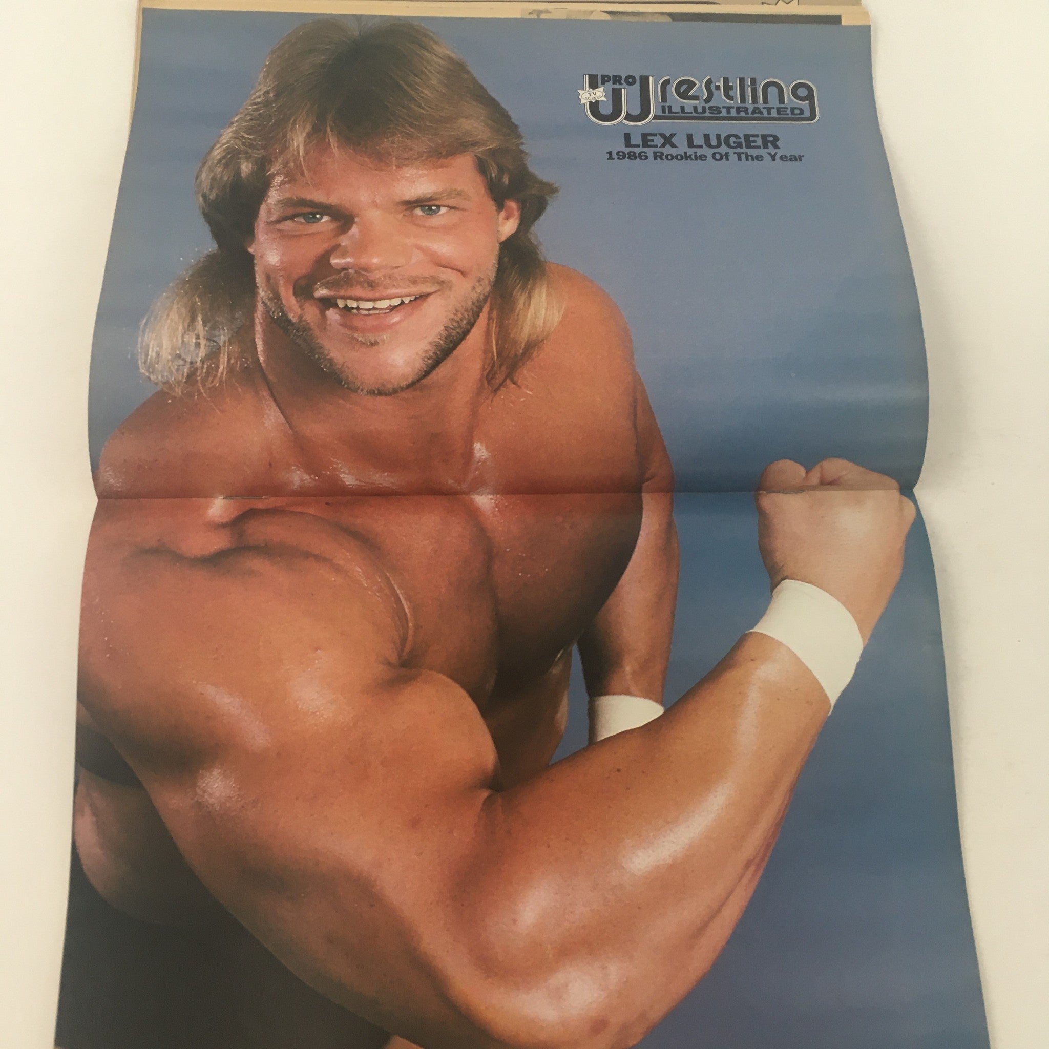 Pro Wrestling Illustrated April 1987 cover featuring Lex Luger, 1986 Rookie of the Year, smiling and flexing his muscles, highlighting iconic wrestling personalities.