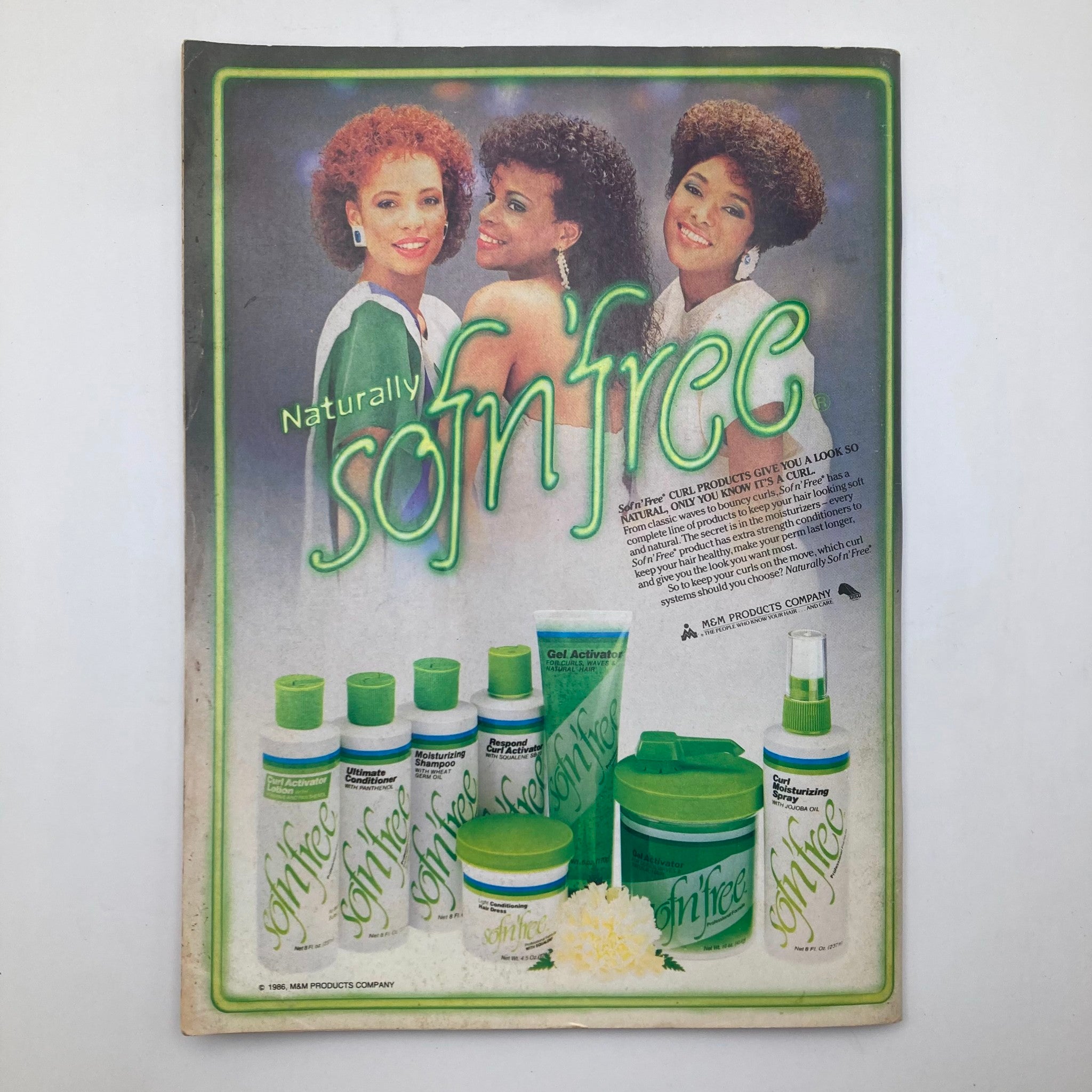 Back cover of Essence Magazine August 1986 showcasing a beauty product advertisement for Naturally Soft'n Free hair care products, featuring models with vibrant hairstyles.