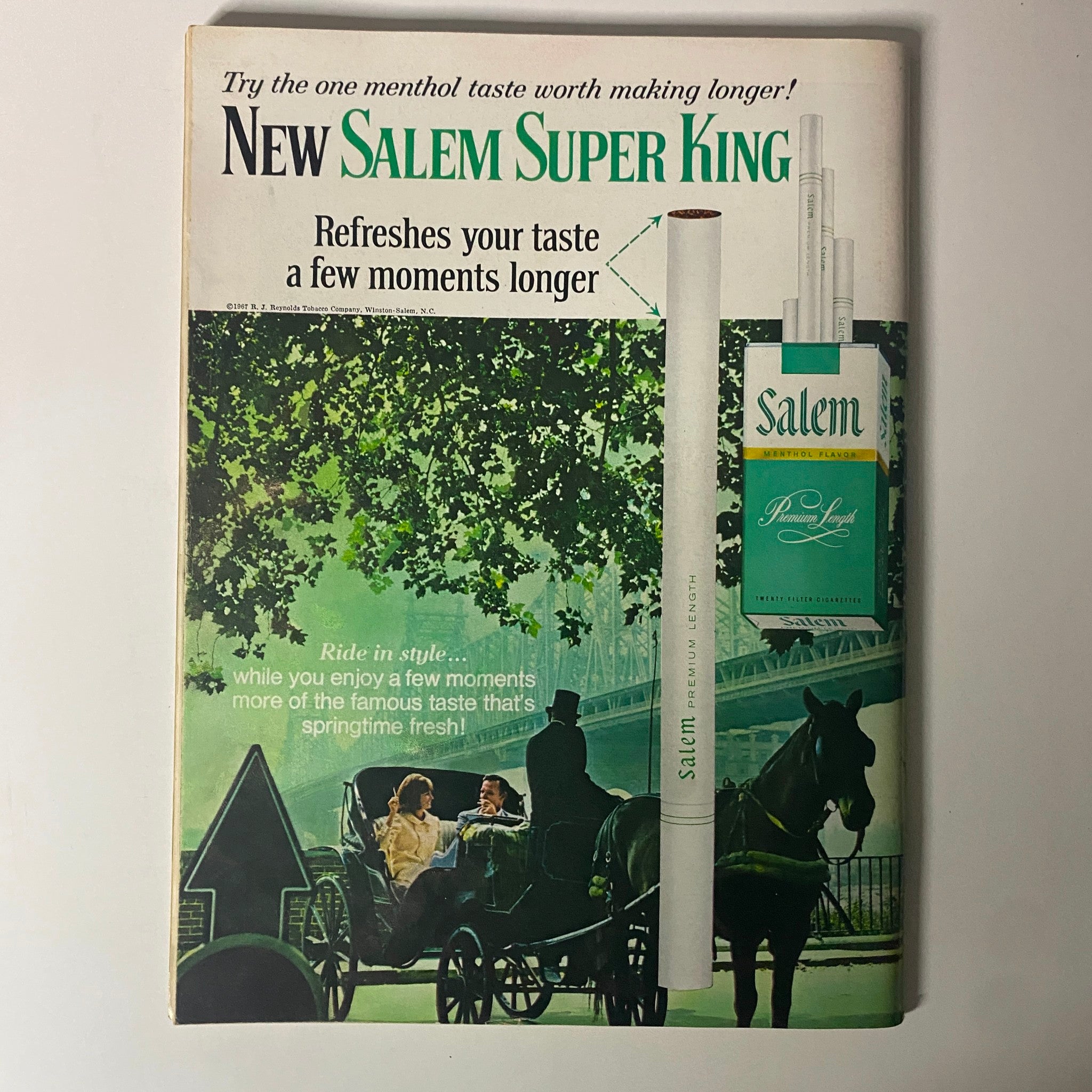 Vintage advertisement for New Salem Super King cigarettes, highlighting the menthol taste, featured on the cover of a magazine. The visual includes a serene outdoor scene with a couple in a horse-drawn carriage, emphasizing the refreshing taste of the product.