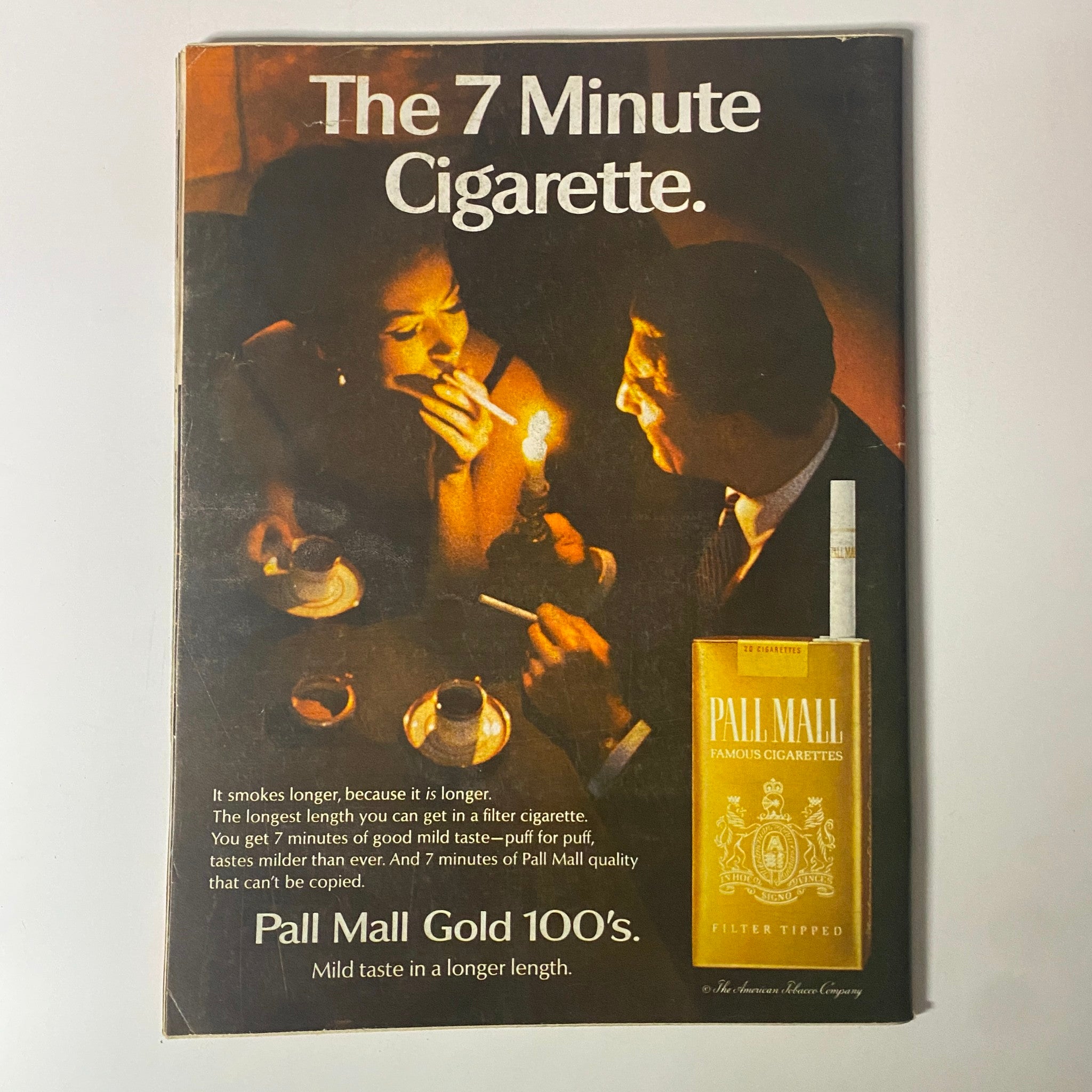 Vintage advertisement for Pall Mall cigarettes featuring a romantic couple, emphasizing the brand's long-lasting, mild taste in the context of the 1960s lifestyle.