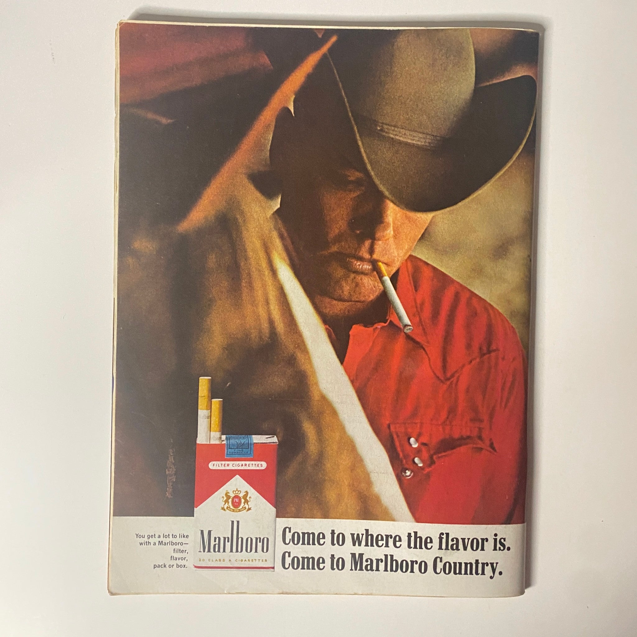 Marlboro advertisement featuring a cowboy with a cigarette, promoting the slogan 'Come to where the flavor is. Come to Marlboro Country.' This image highlights rugged individuality and the iconic Marlboro branding.