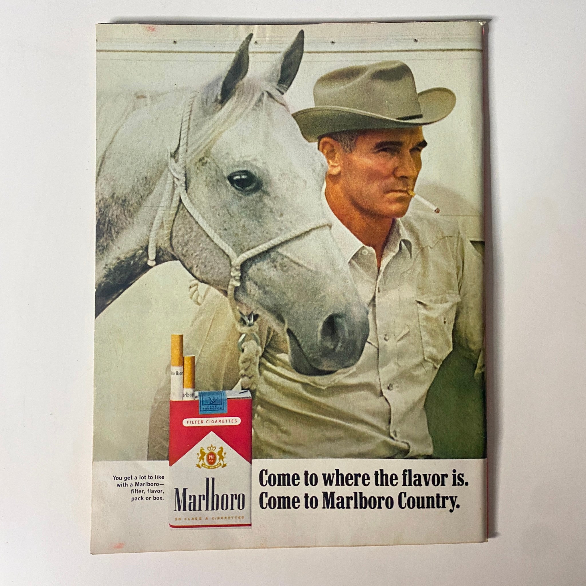 Advertisement page for Marlboro cigarettes from a vintage magazine, depicting a cowboy with a horse, promoting the lifestyle associated with the brand.