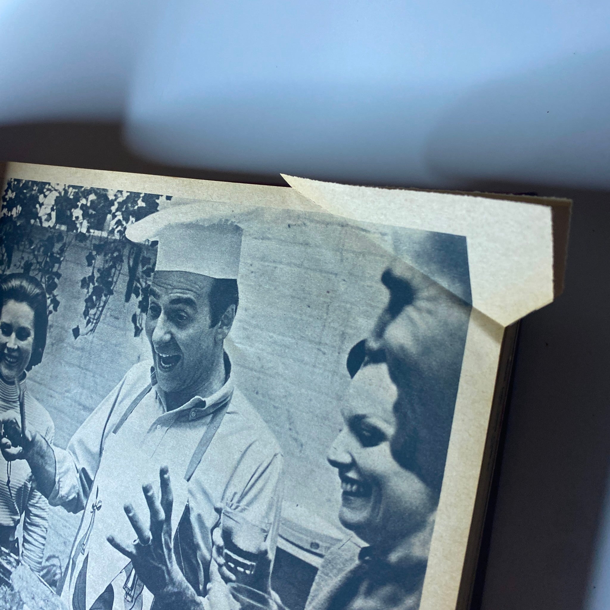 A candid shot from The New York Times Magazine July 1965, capturing a chef in a white hat joyfully engaging with two women at a social gathering.