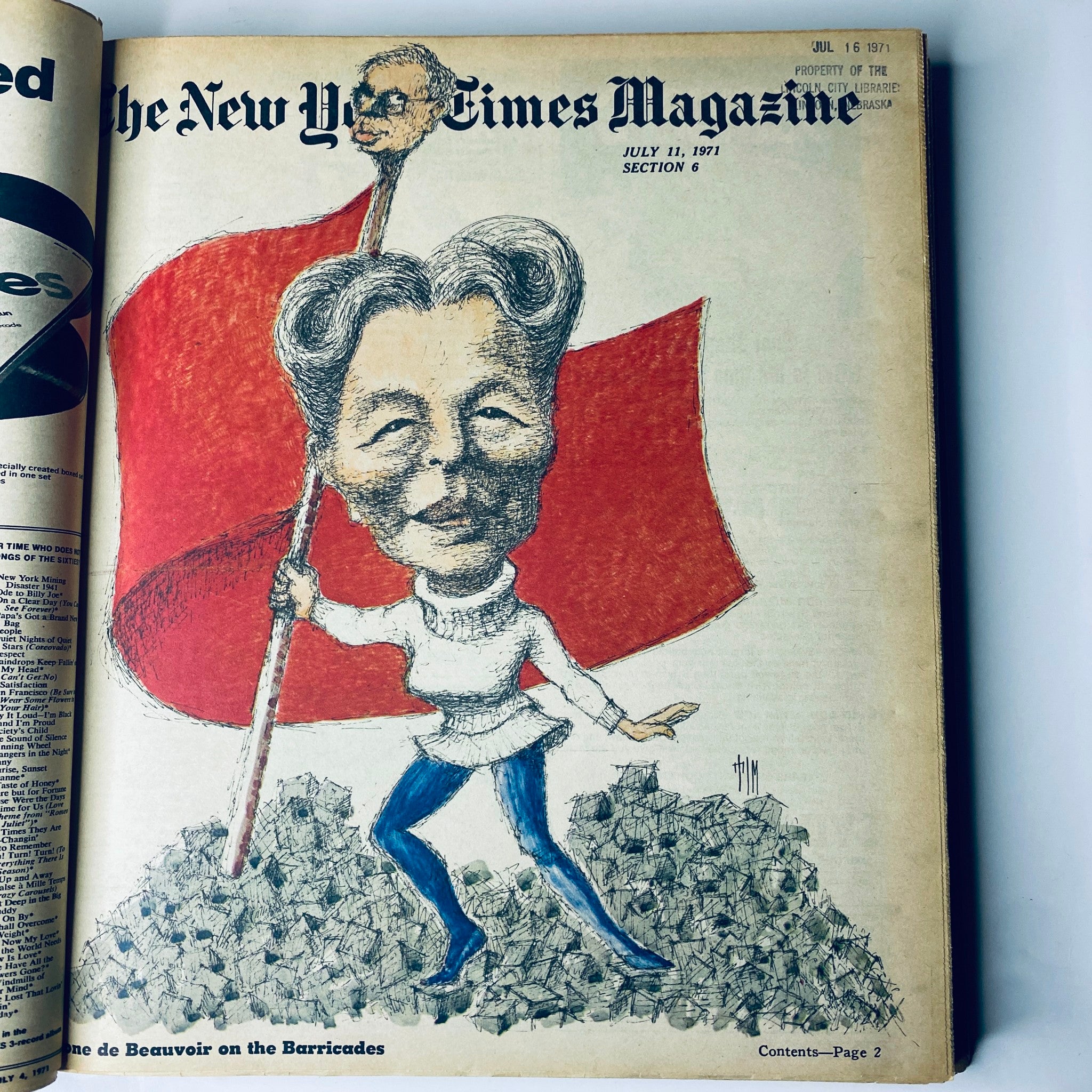 Cover page of The New York Times Magazine, July 11, 1971, showcasing a caricature of Simone de Beauvoir holding a red flag amid a pile of crushed rocks.