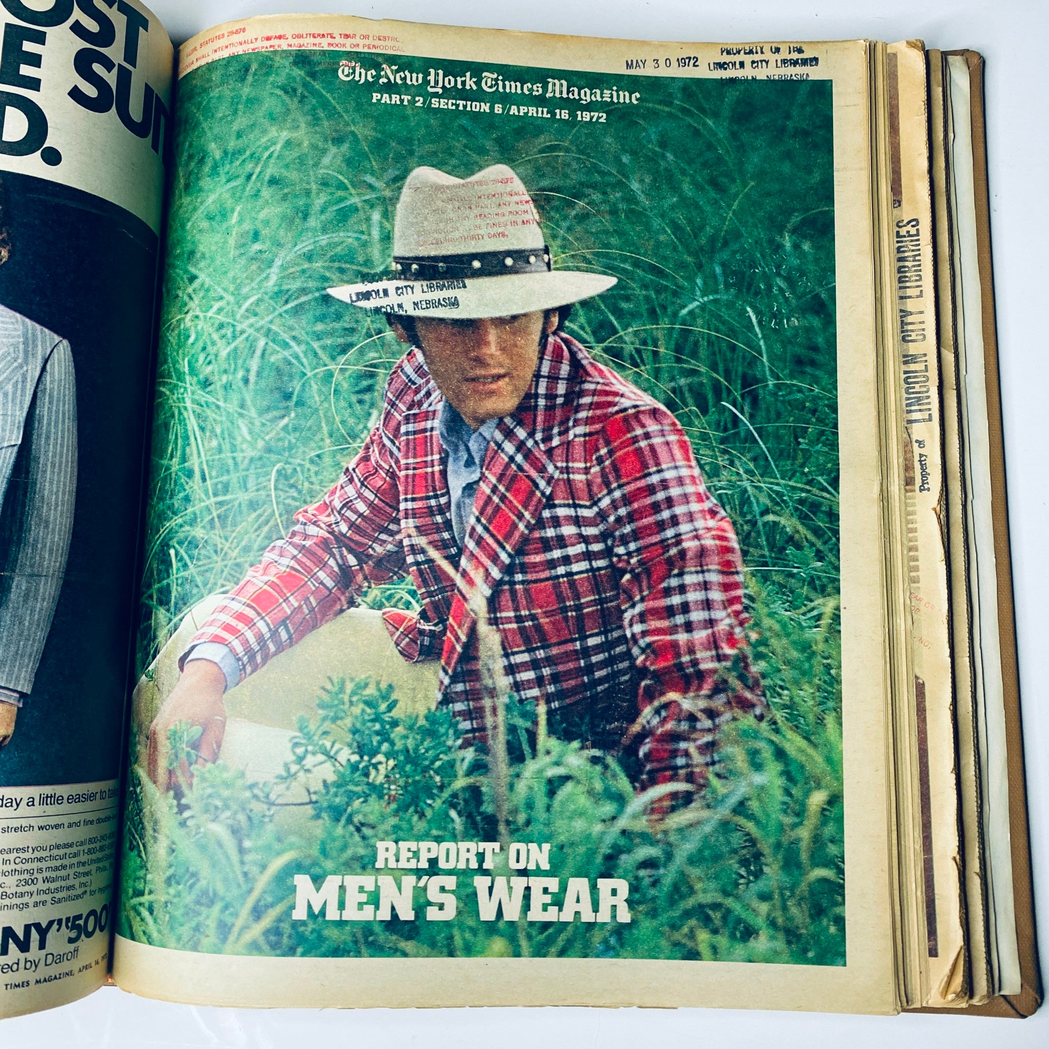 Interior page of The New York Times Magazine, April 30, 1972, presenting a fashion report on men's wear, with a male model wearing a plaid suit in an outdoor setting, marked 'Lincoln City Library'.