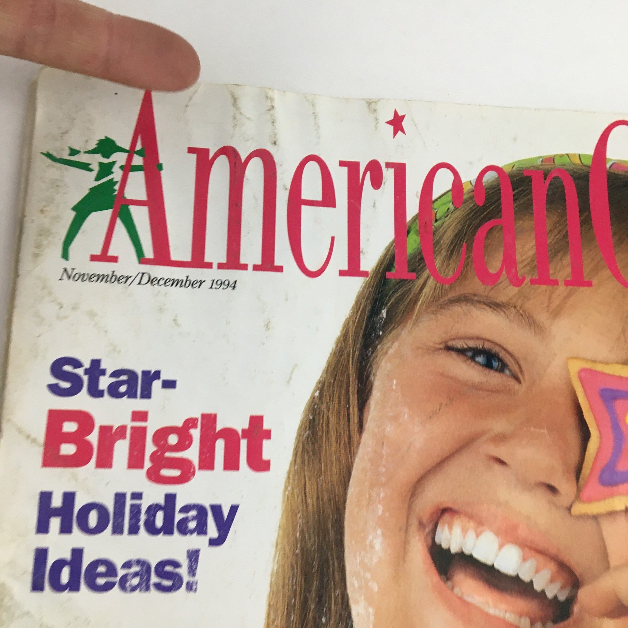 Close-up of the cover of American Girl Magazine November 1994, highlighting the title 'Star-Bright Holiday Ideas!' and a joyful girl showcasing a cookie, emphasizing fun and festive themes.