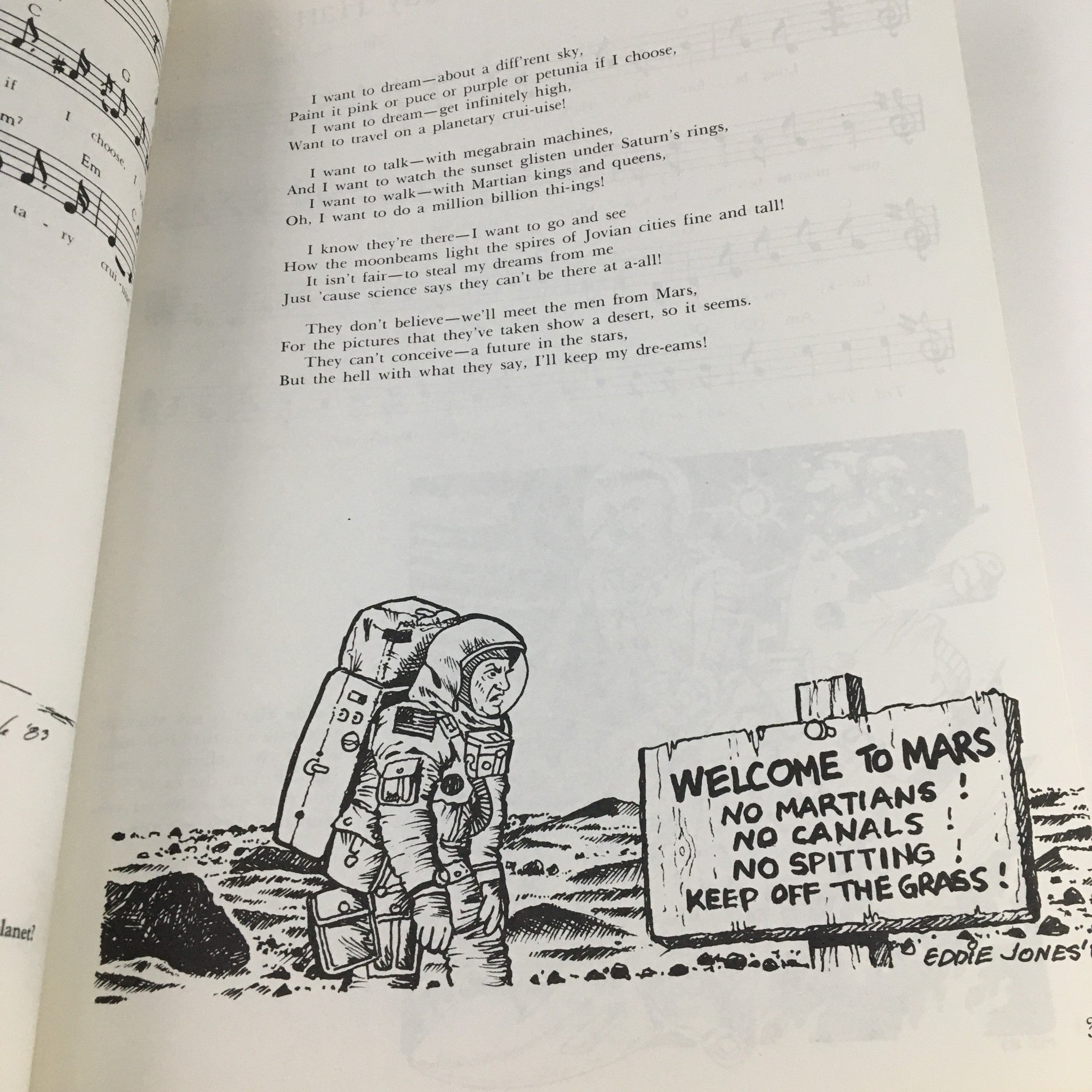 Another interior page from 1988 A New Settlement of Old Scores by John Brunner, highlighting lyrics and musical notation with a humorous illustration of an astronaut in front of a sign labeled 'Welcome to Mars'.
