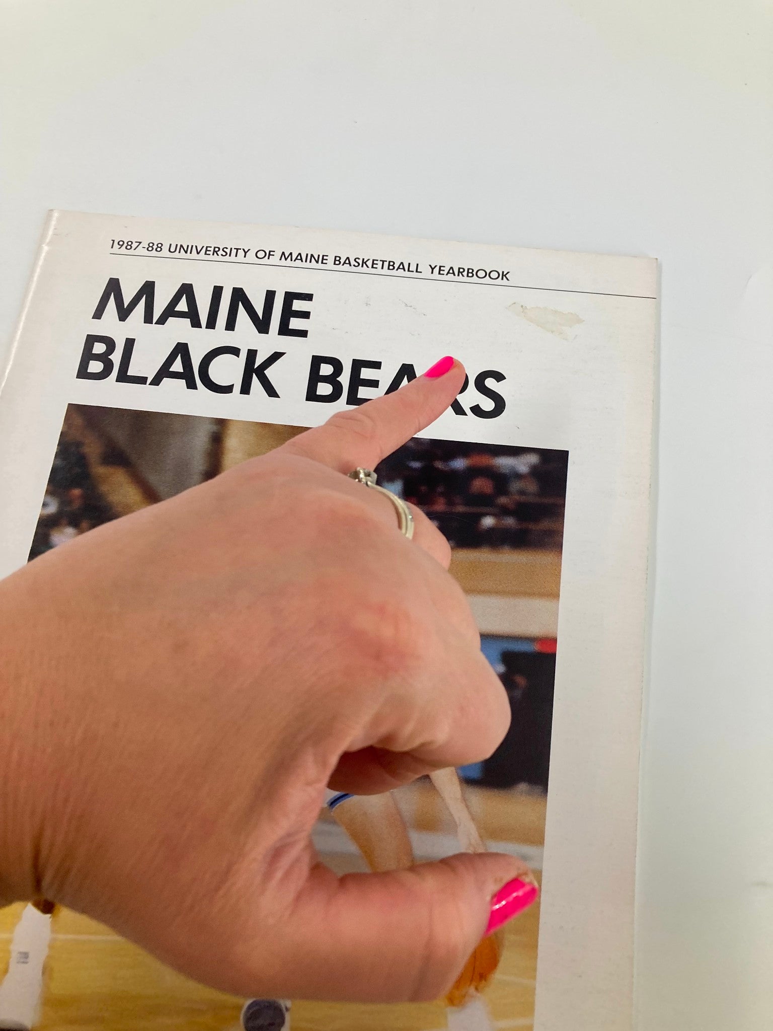 Close-up of the 1987-88 University of Maine Basketball Yearbook cover highlighting the Maine Black Bears title with a hand pointing to the top.