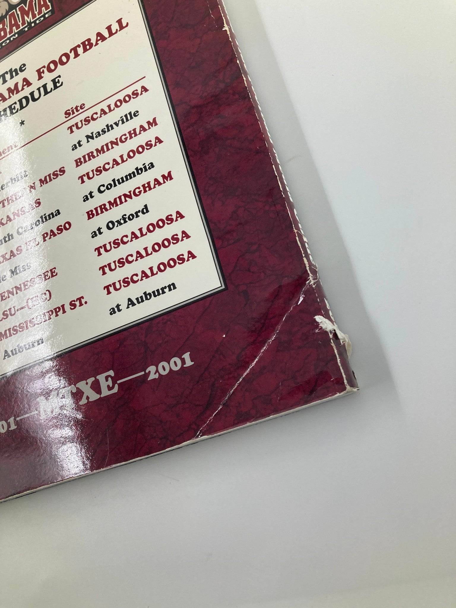 Close-up of the back cover of the 2001 Alabama Crimson Tide Football Official Program showing damage and the football schedule.