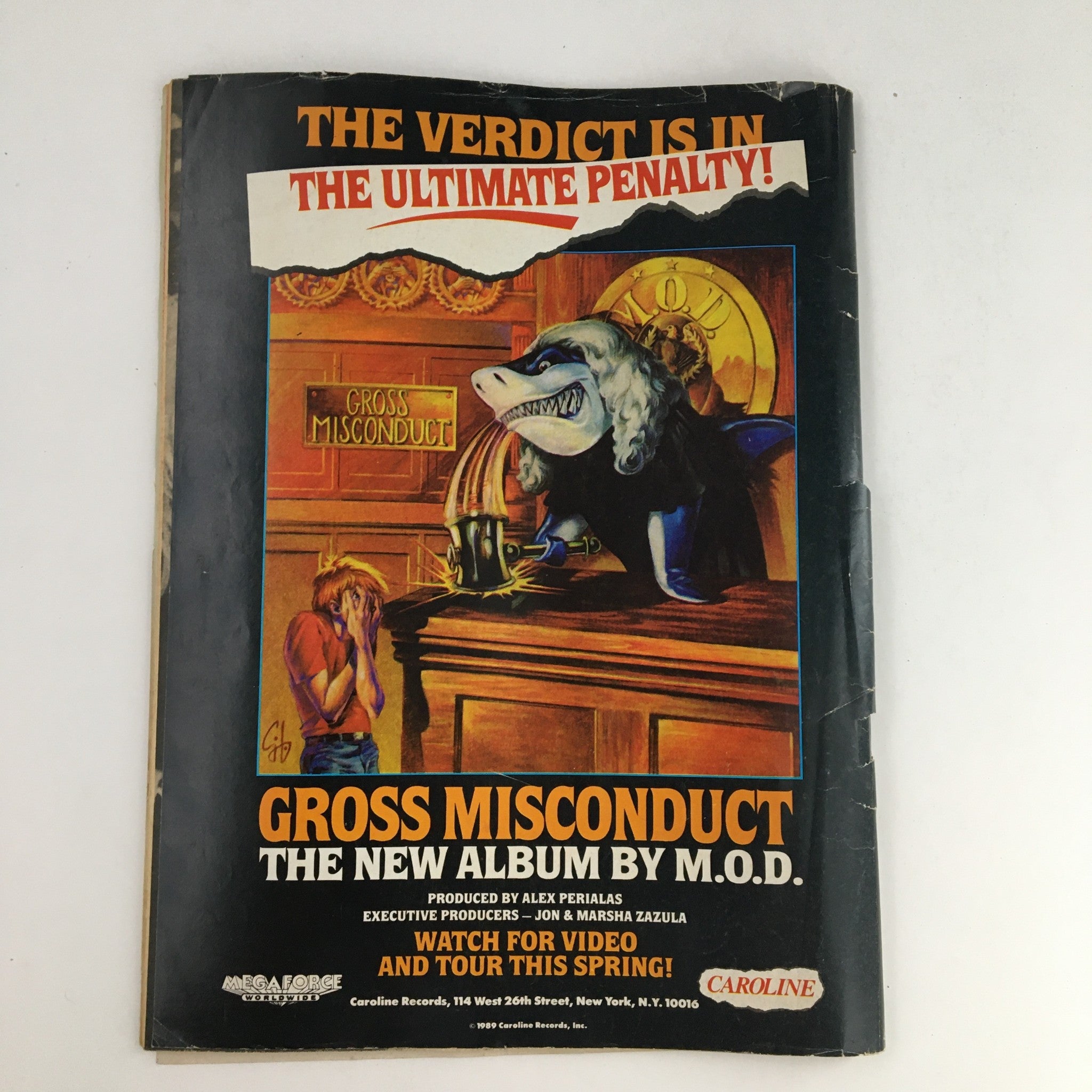 Advertisement in Hit Parader Power Metal June 1989 for the album 'Gross Misconduct' by M.O.D., featuring an illustrated courtroom scene with a dog character.