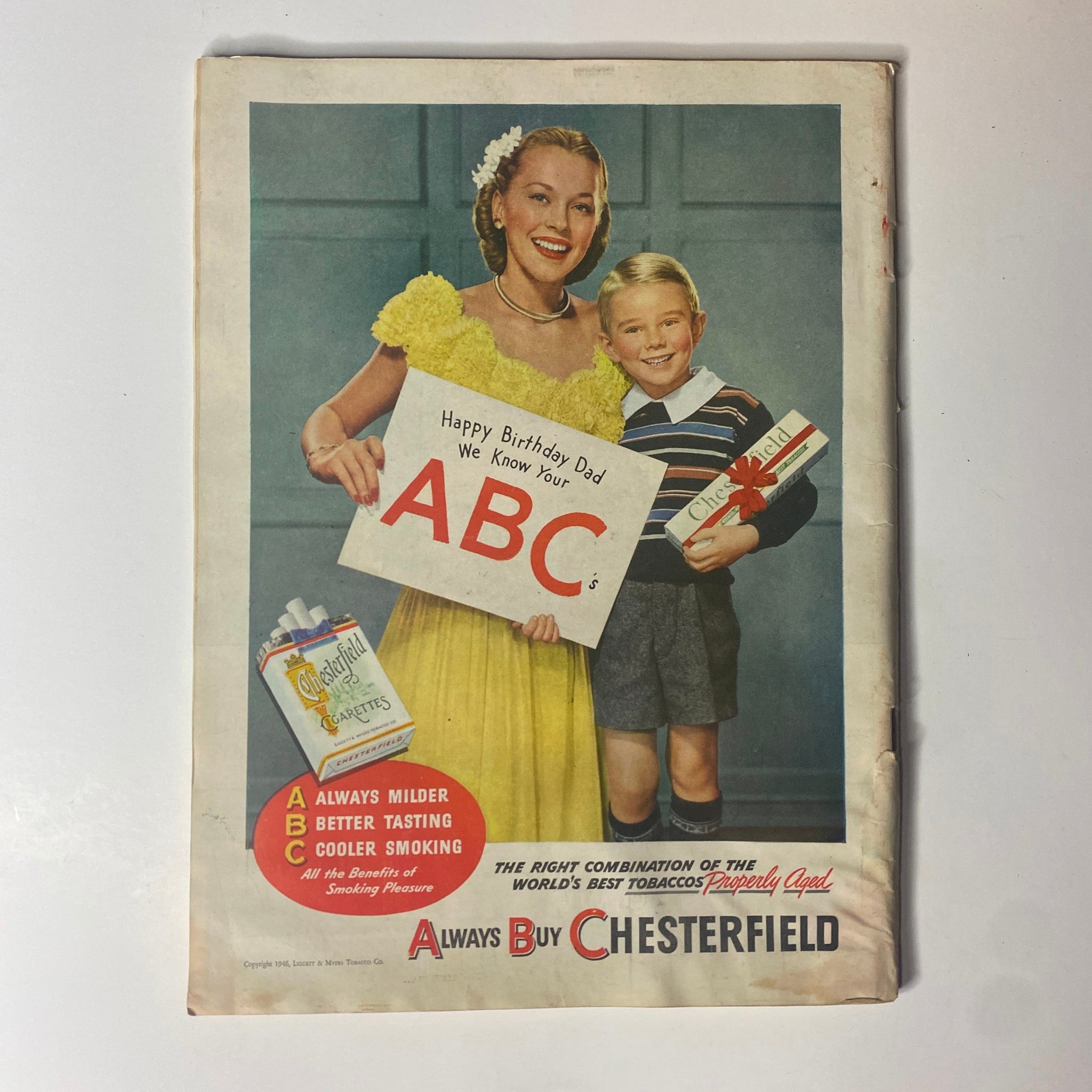Vintage advertisement from a magazine featuring a smiling woman in a yellow dress and a boy holding a birthday sign. The ad promotes Chesterfield cigarettes with the tagline 'Always Buy Chesterfield.'