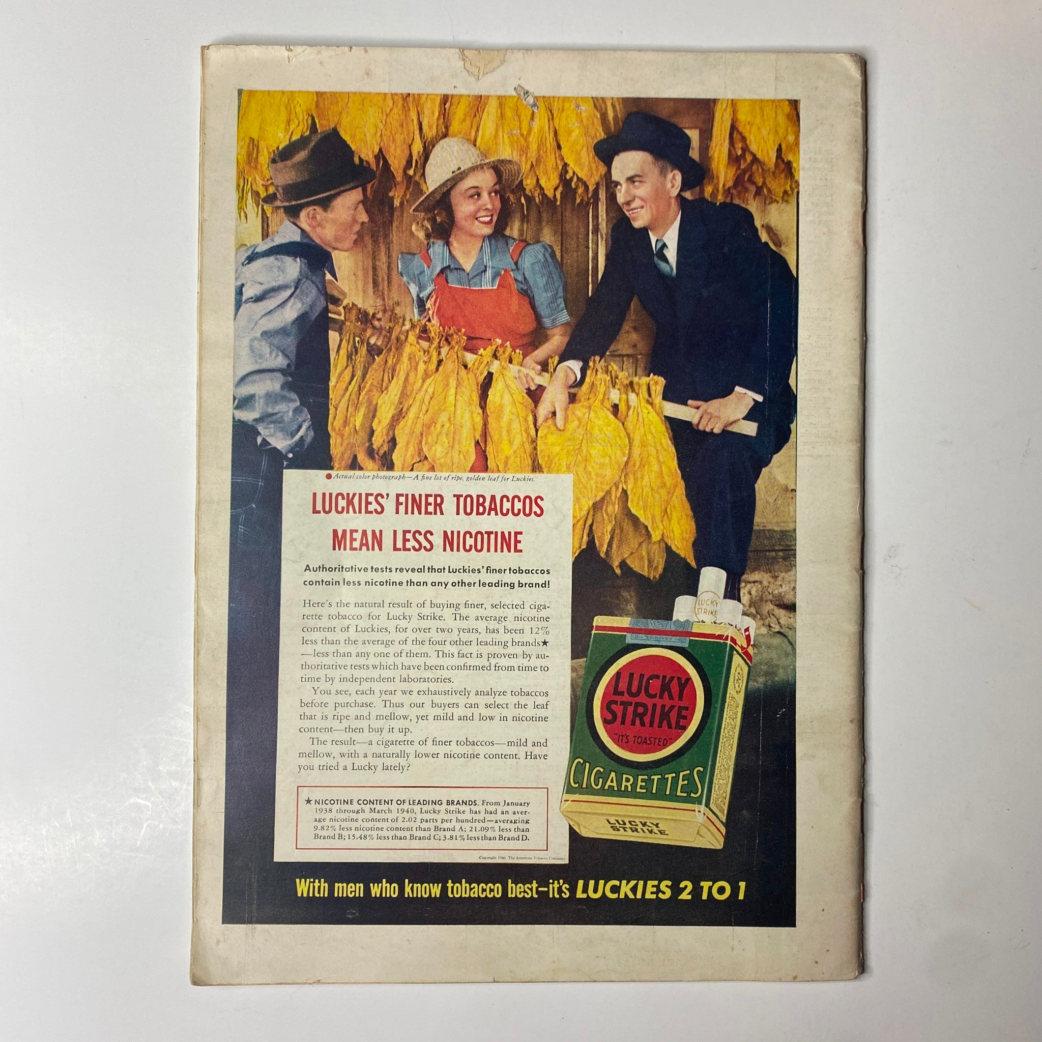 Advertorial page for Lucky Strike cigarettes, showcasing men and women with tobacco plants, promoting the brand's lower nicotine content, from a vintage publication.