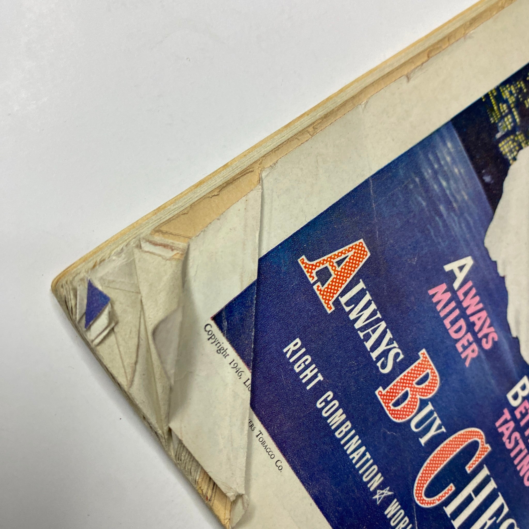Close-up view of the damaged corner of a vintage Chesterfield cigarette advertisement from 1946, showcasing the wear and tear that comes with age.