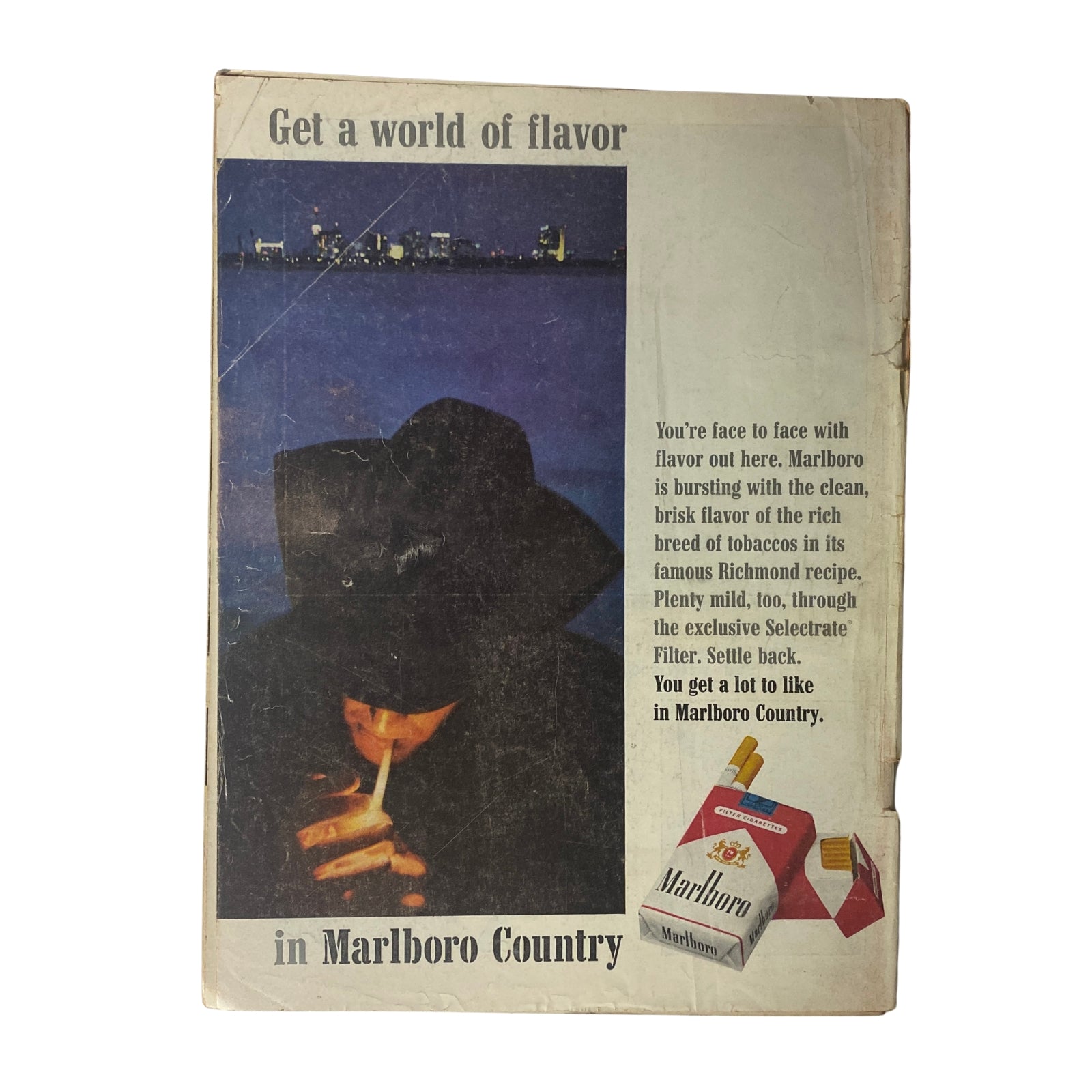 Back cover of a magazine, featuring a Marlboro advertisement with the tagline 'Get a world of flavor in Marlboro Country', showcasing a person smoking.