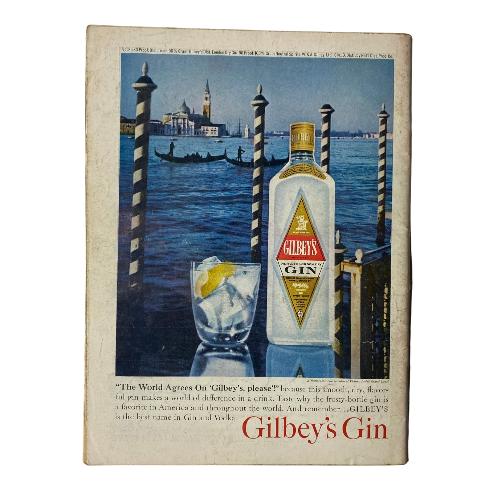 Back cover advertisement for Gilbey's Gin, depicting a frosty bottle of gin with a glass and lemon slice against a scenic Venetian backdrop.