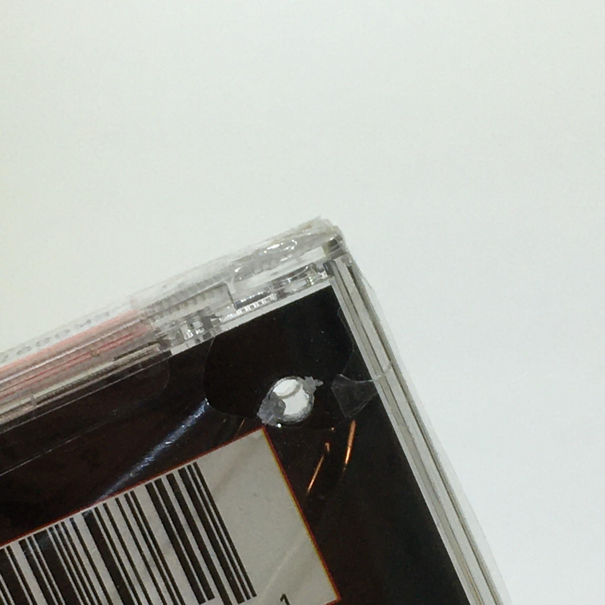 Close-up of the cut-out hole on the plastic case of 'Confessions Of Fire by Cam'Ron Music Audio CD Factory Sealed', indicating it is a cut-out copy.
