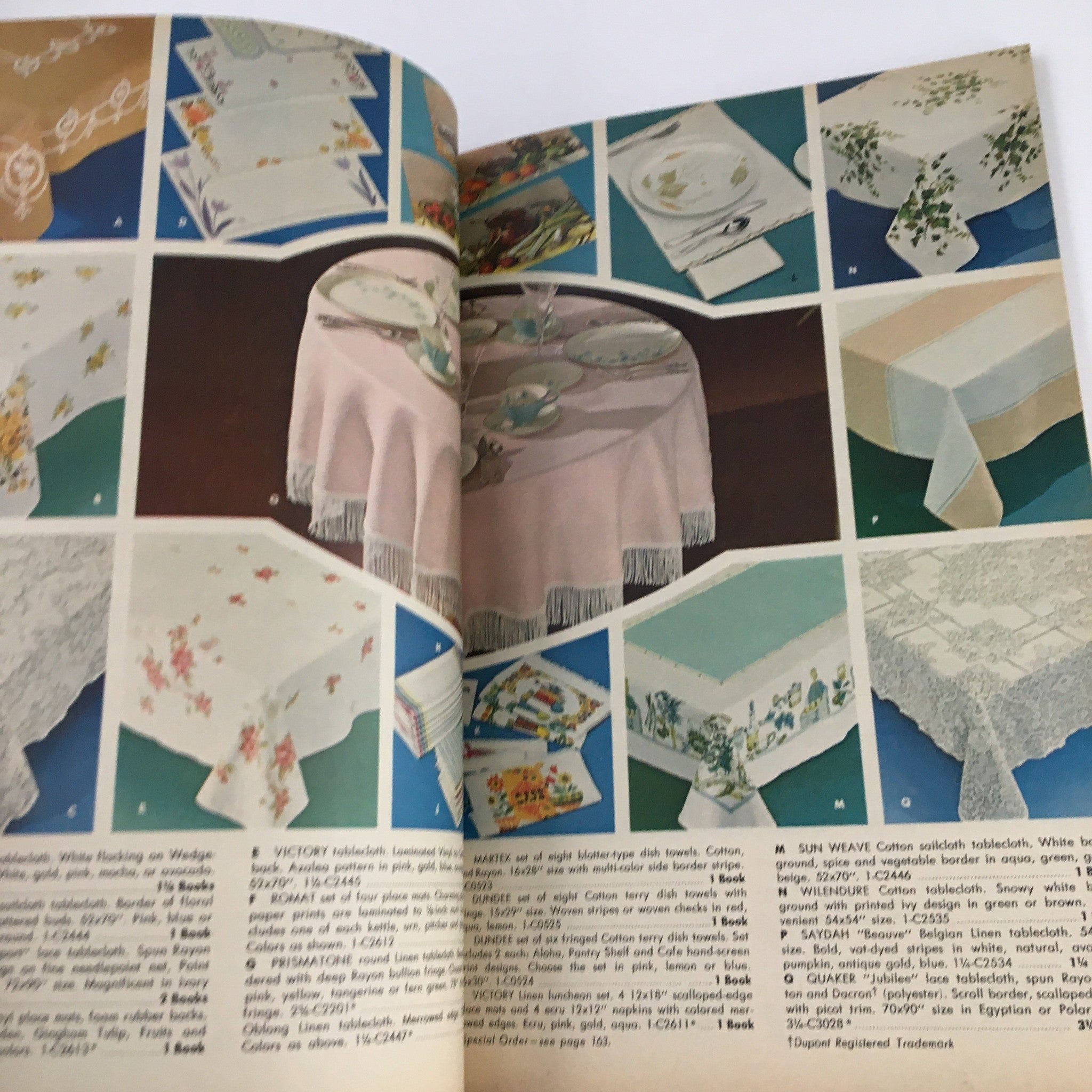 Page from S&H Green Stamps Distinguished Merchandise 1963 displaying an assortment of tablecloths and dishes, showcasing products for elegant dining settings.