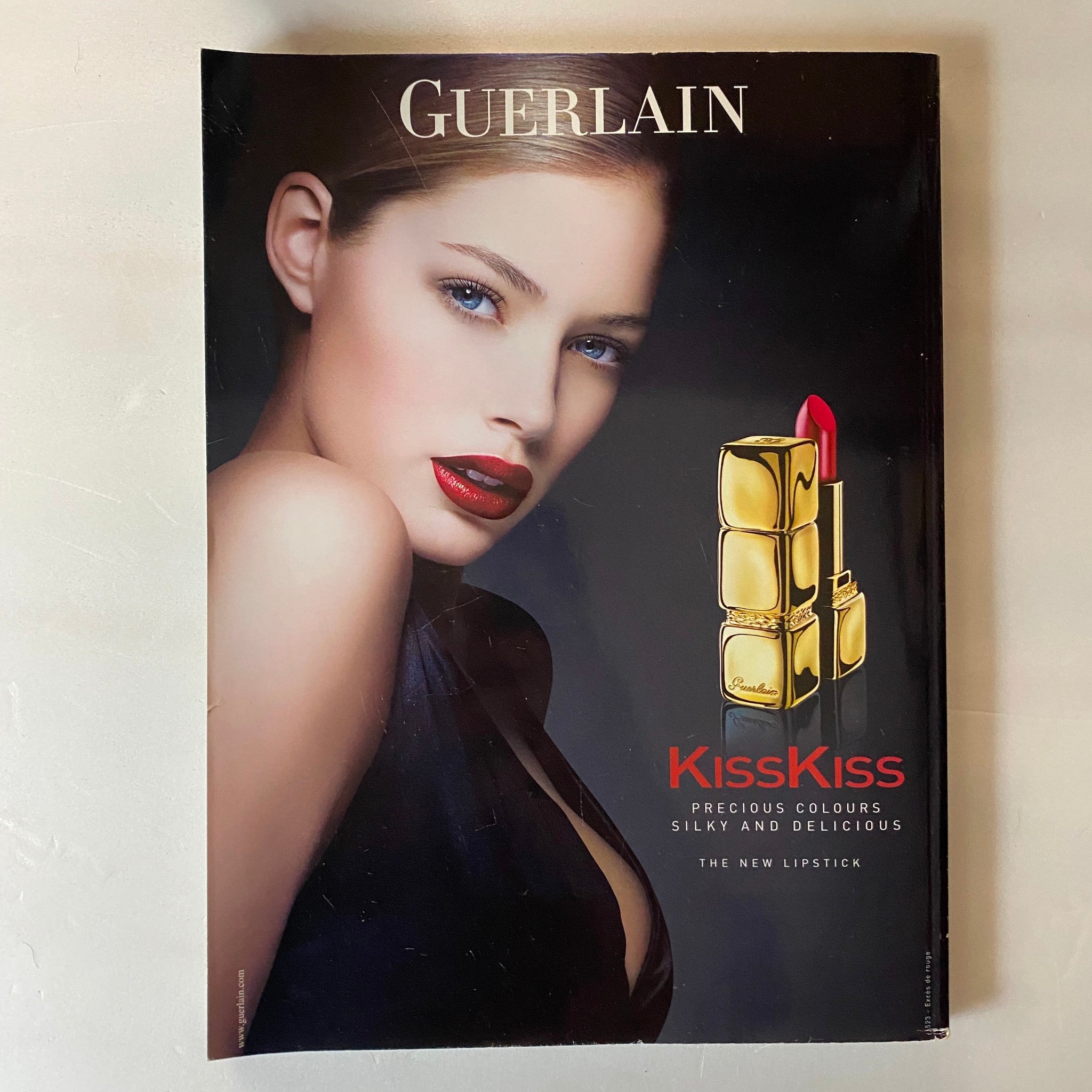 Advertisement page featuring Guerlain's KissKiss lipstick in Harpers & Queen UK Magazine December 2005, showcasing bold beauty trends.