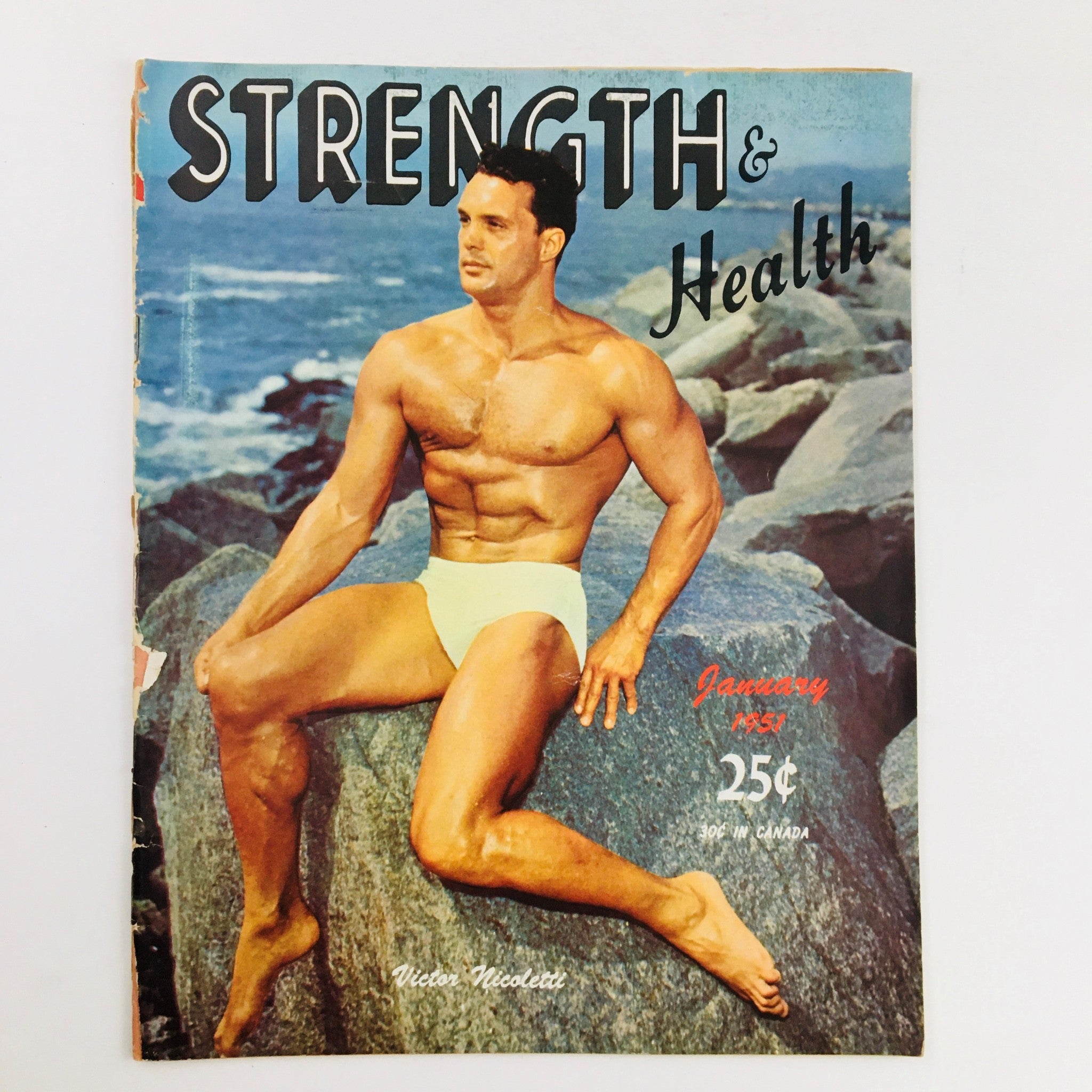 Cover of Strength & Health Magazine January 1951 featuring bodybuilder Victor Nicolett with a rocky beach background.