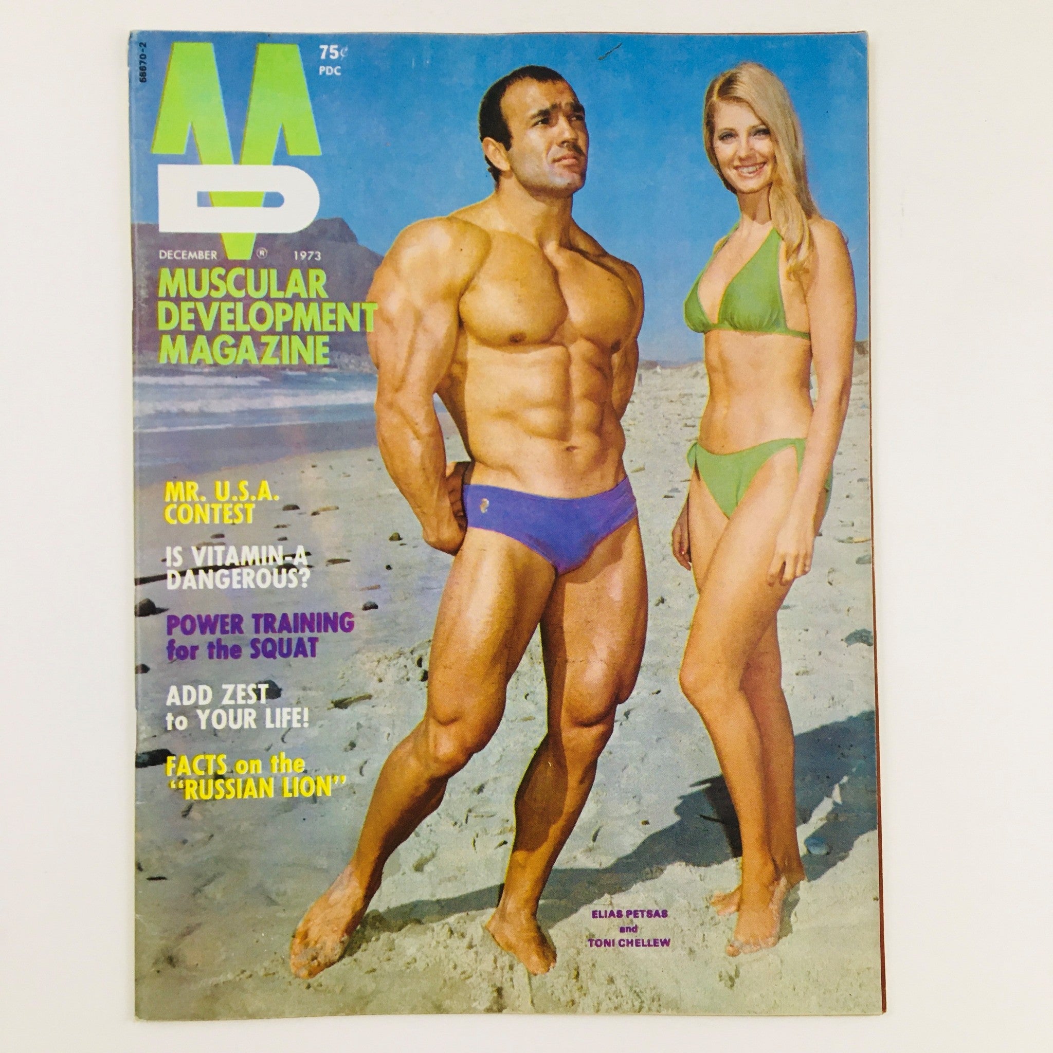 Cover of Muscular Development Magazine December 1973 featuring muscular male model Elias Petsas and female model Toni Chellew on a beach backdrop. Captures the essence of the vintage bodybuilding culture from the early 1970s.