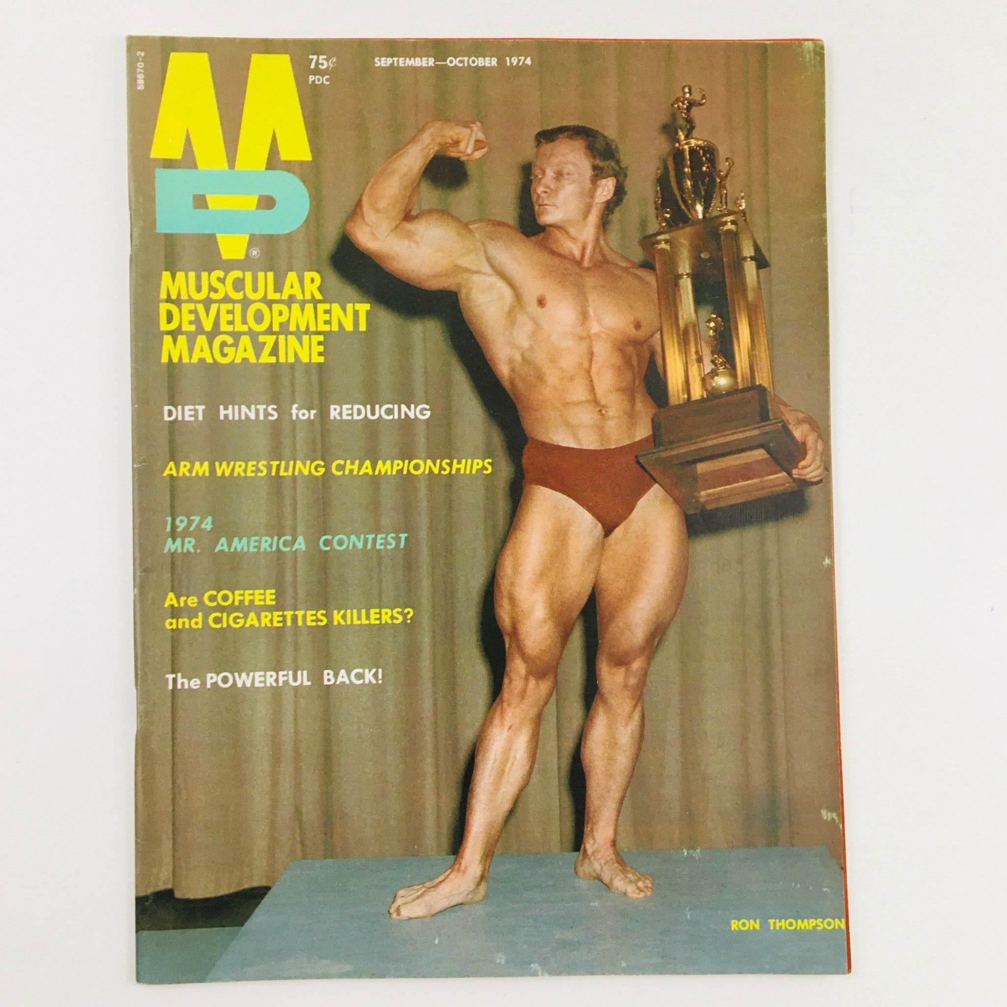 Cover of Muscular Development Magazine September 1974 featuring Ron Thompson, posing with a trophy, showcasing vintage bodybuilding culture.