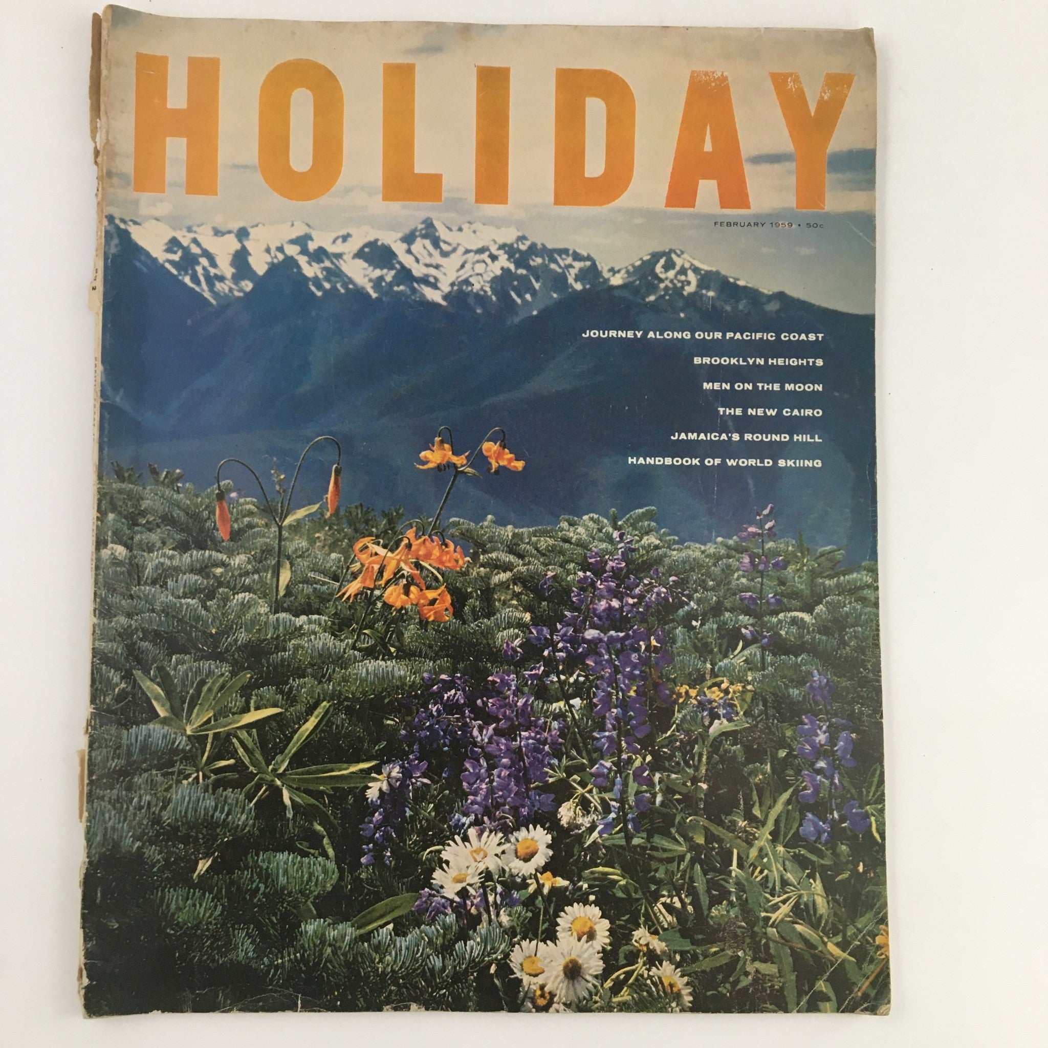 Cover of Holiday Magazine February 1959 featuring a scenic view along the Pacific Coast with vibrant flowers and mountains.