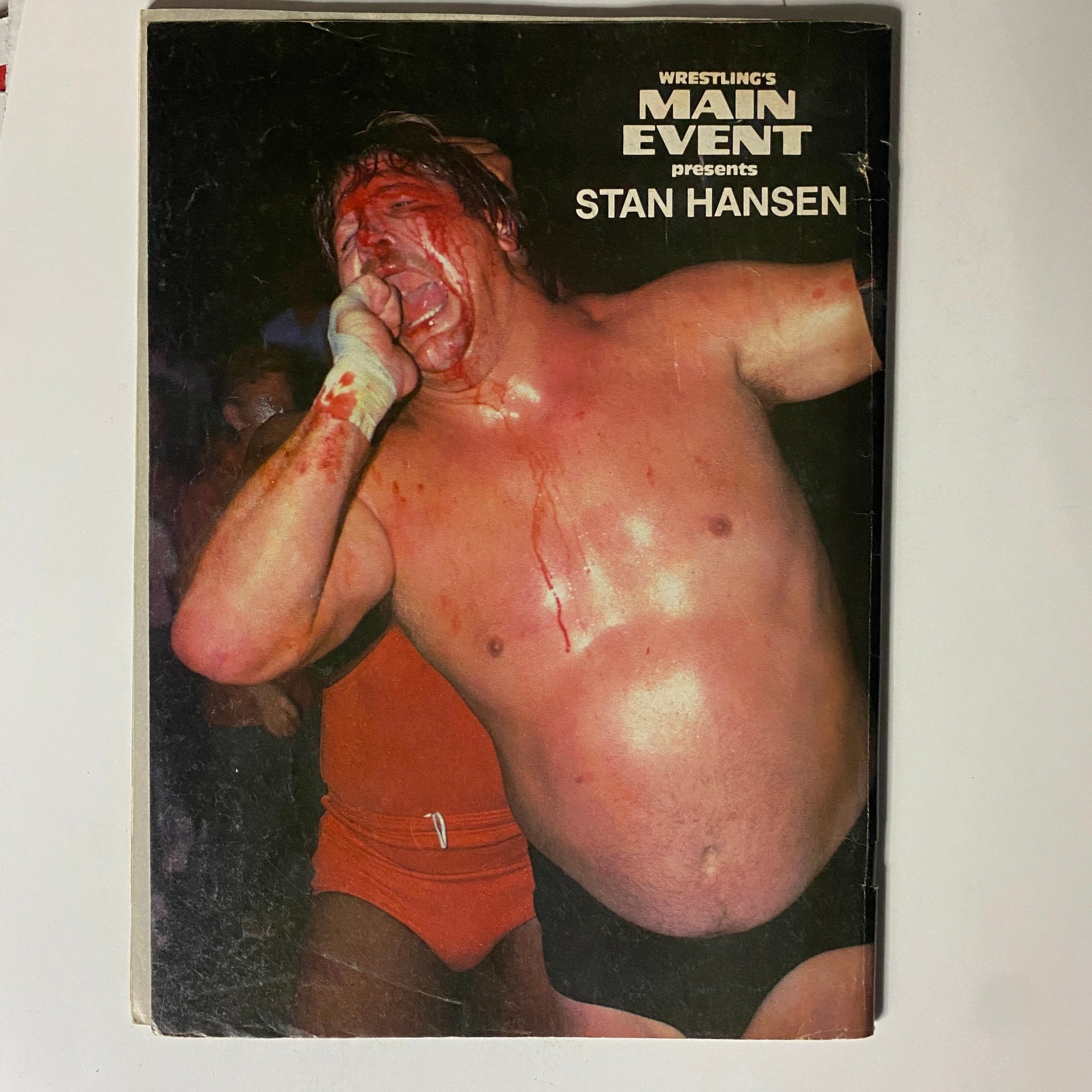 Cover of VTG Wrestling's Main Event Magazine April 1986 featuring iconic wrestler Stan Hansen. The image showcases a dramatic moment with Stan Hansen, who appears visibly bloodied, emphasizing the intense nature of professional wrestling. This collectible magazine captures the essence and excitement of wrestling in the mid-1980s.