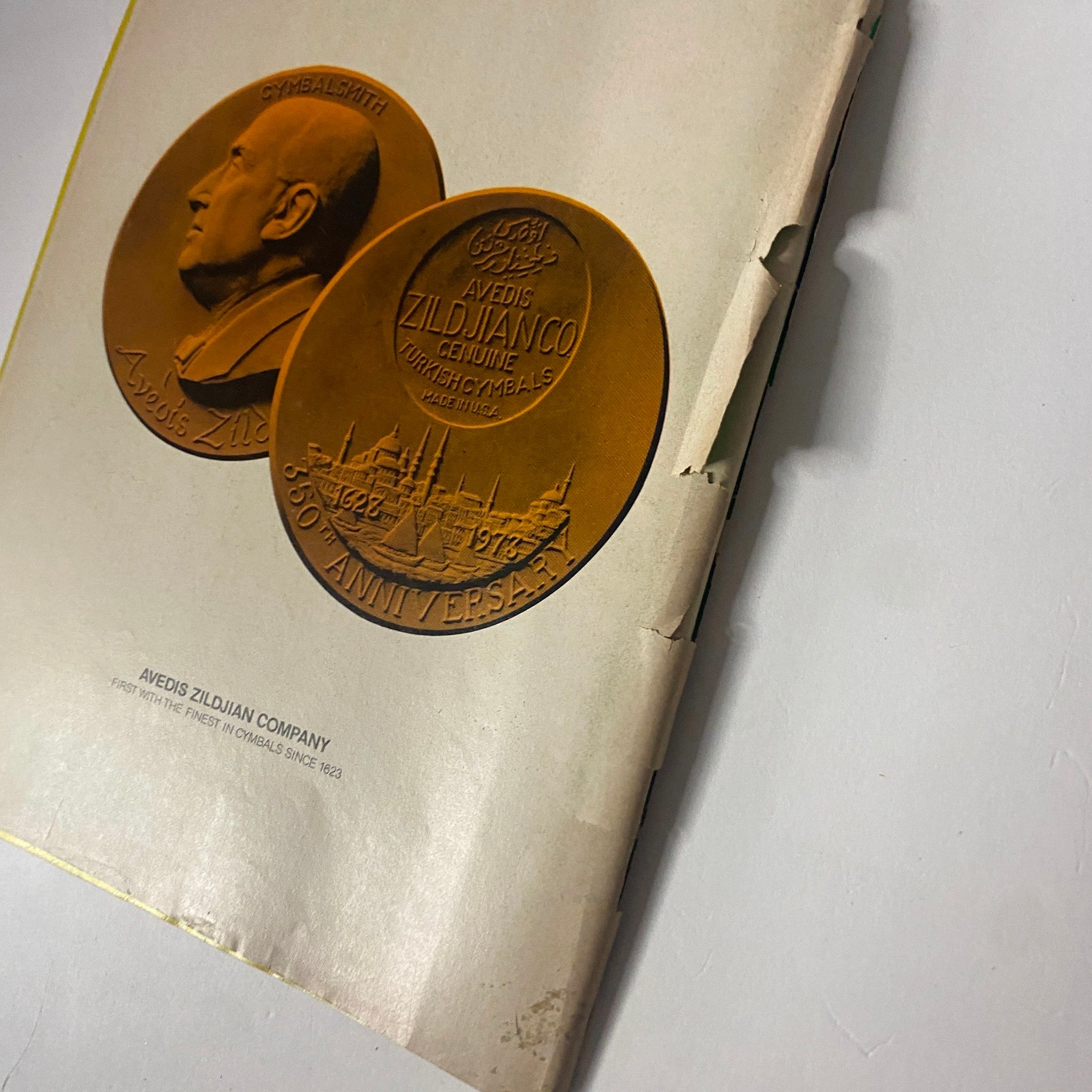 Close-up of the cover page commemorating the 350th anniversary of Avedis Zildjian Company, showing the medals and the company logo.