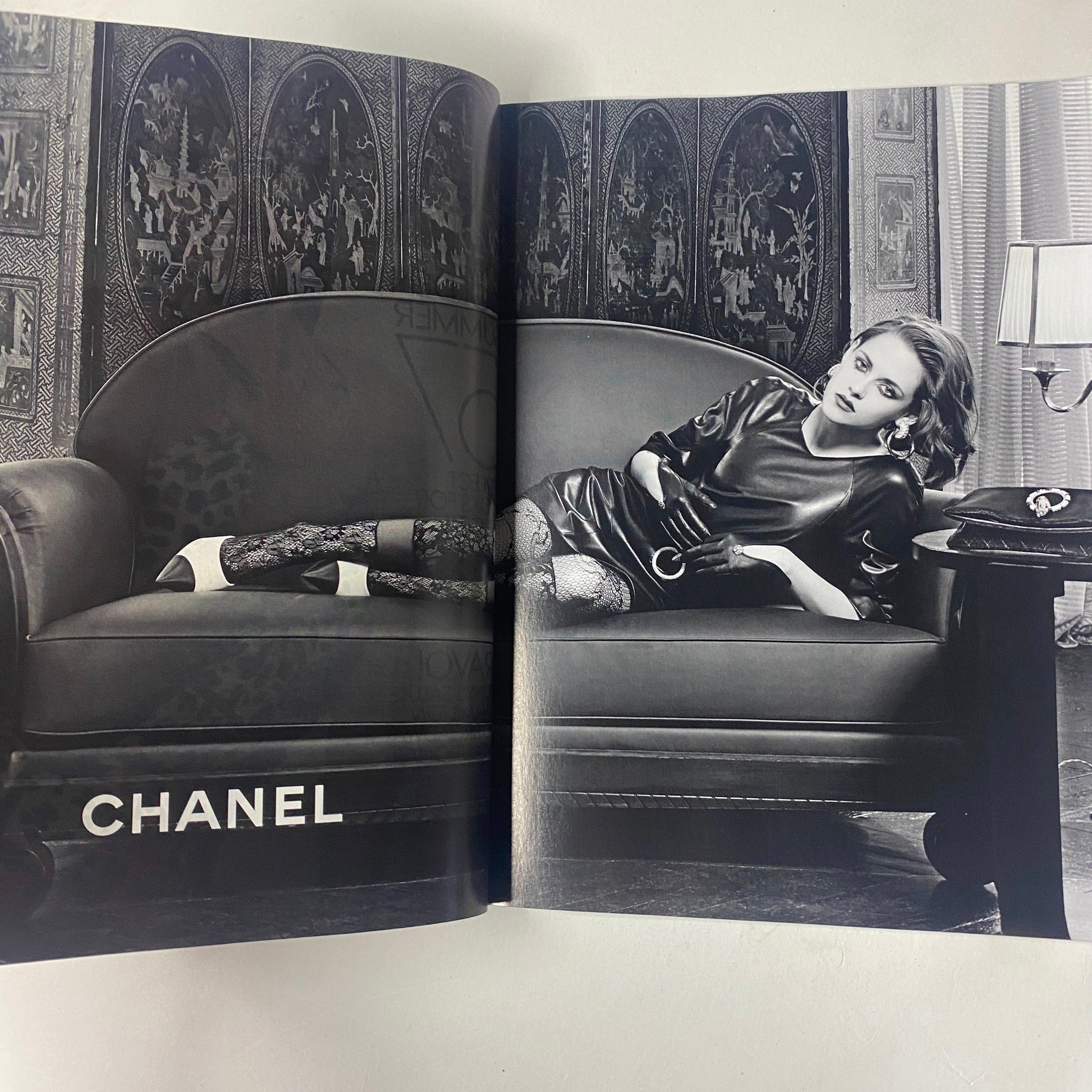 Vogue Magazine June 2016 Margot Robbie Cover showcases a striking black and white image featuring a model lounging on a couch, wearing Chanel fashion accessories, emphasizing luxury and elegance.