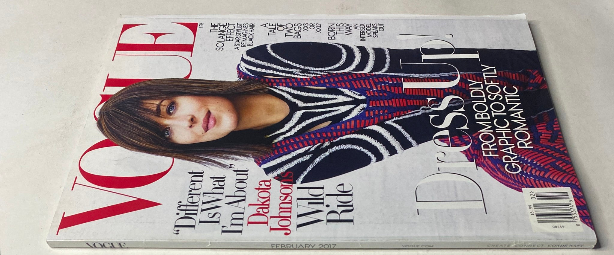Side view of the Vogue Magazine February 2017 showcasing Dakota Johnson on the cover, embellished with the title 'Vogue Magazine February 2017 Dakota Johnson Cover No Label VG'. The image captures the magazine's artistic design and vibrant colors.