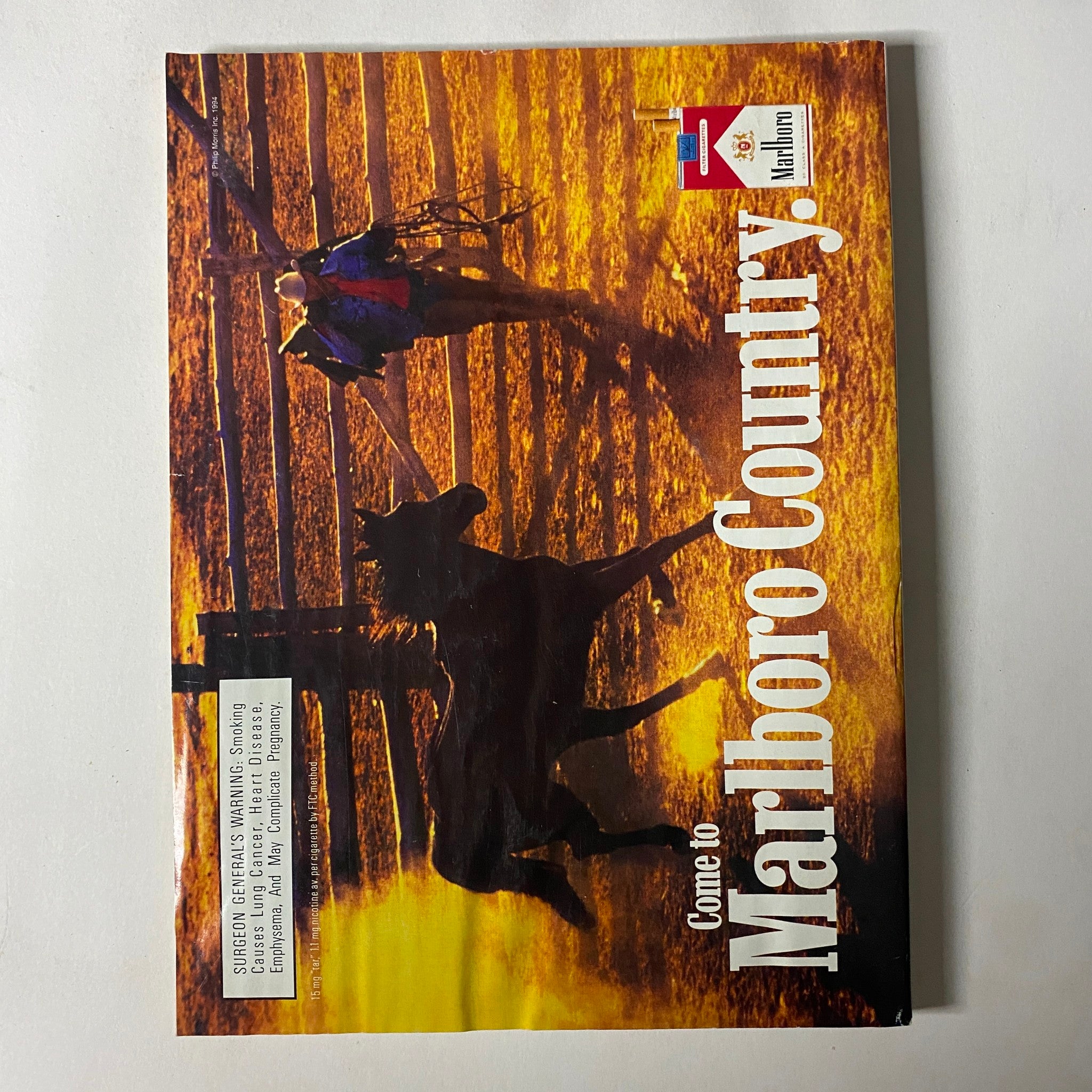 Vintage advertisement for Marlboro Country showcasing a cowboy on horseback with a picturesque landscape background. Part of the collection, titled 'Come to Marlboro Country', this image relates to the iconic themes of adventure and nature associated with the Marlboro brand.