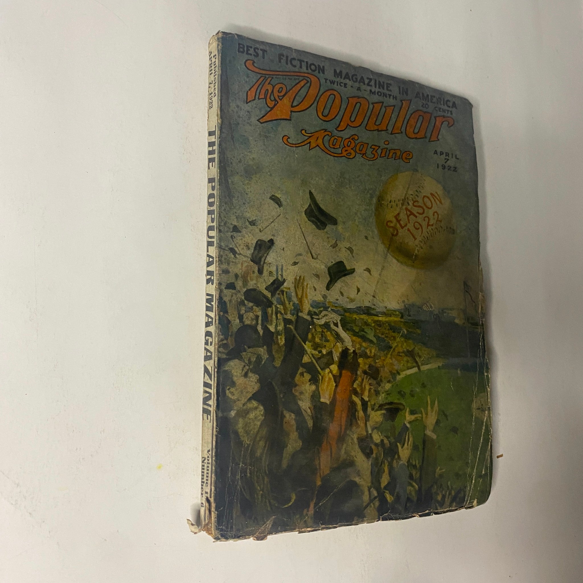 Side view of The Popular Magazine April 7, 1922 showcasing the vibrant cover design with an illustration of people celebrating outdoors, highlighting the magazine's allure and quality.