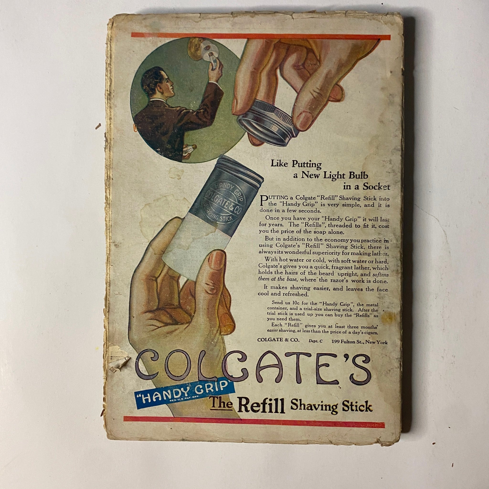 Back cover of Colgate's 'Handy Grip' shaving stick, illustrating the product's use with a detailed visual showing a hand holding the shaving stick. This advertisement showcases the 1920s product design and marketing style.
