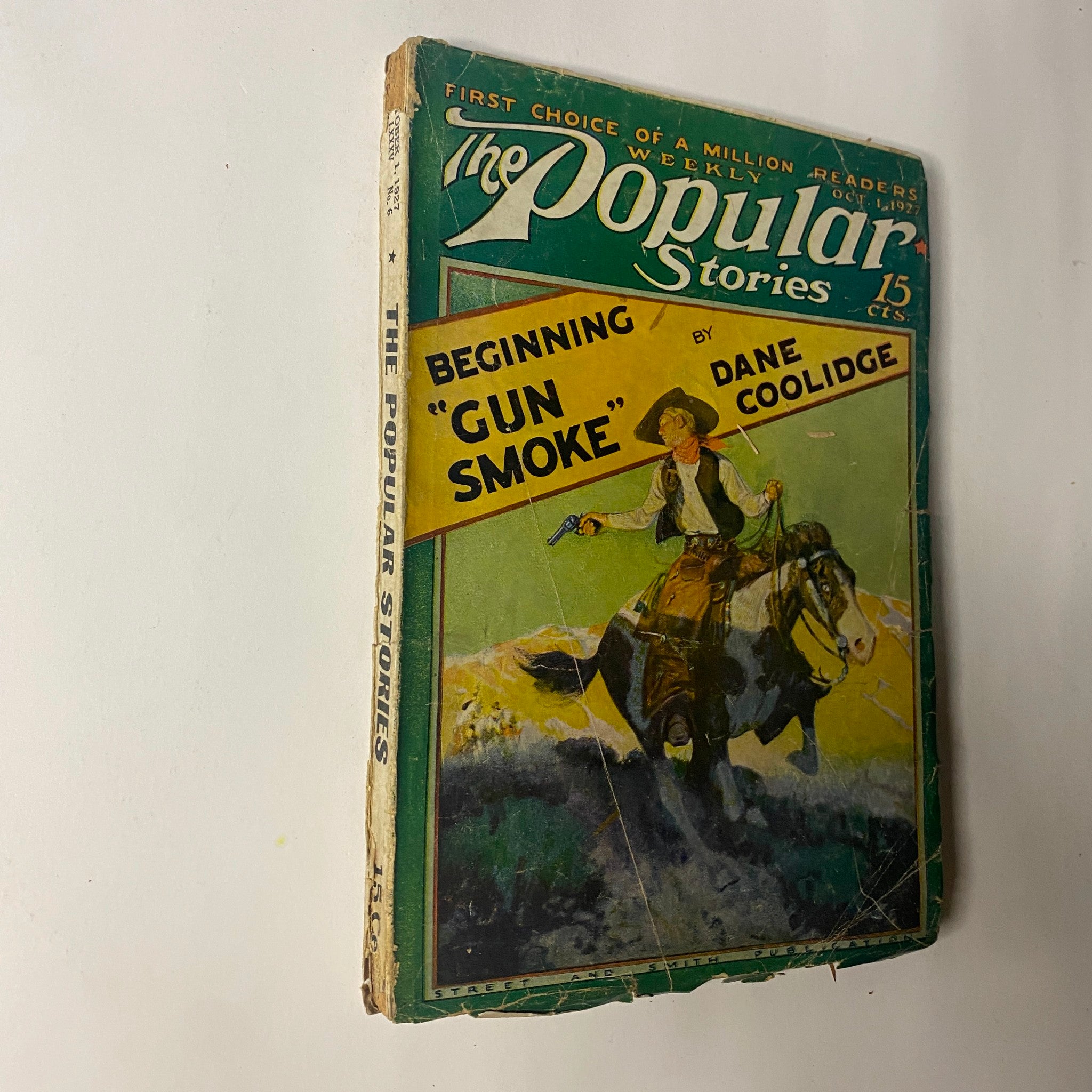 Front cover of The Popular Magazine, October 1, 1927, showcasing the beginning of "Gun Smoke" by Dane Coolidge, illustrated with a cowboy riding a horse.