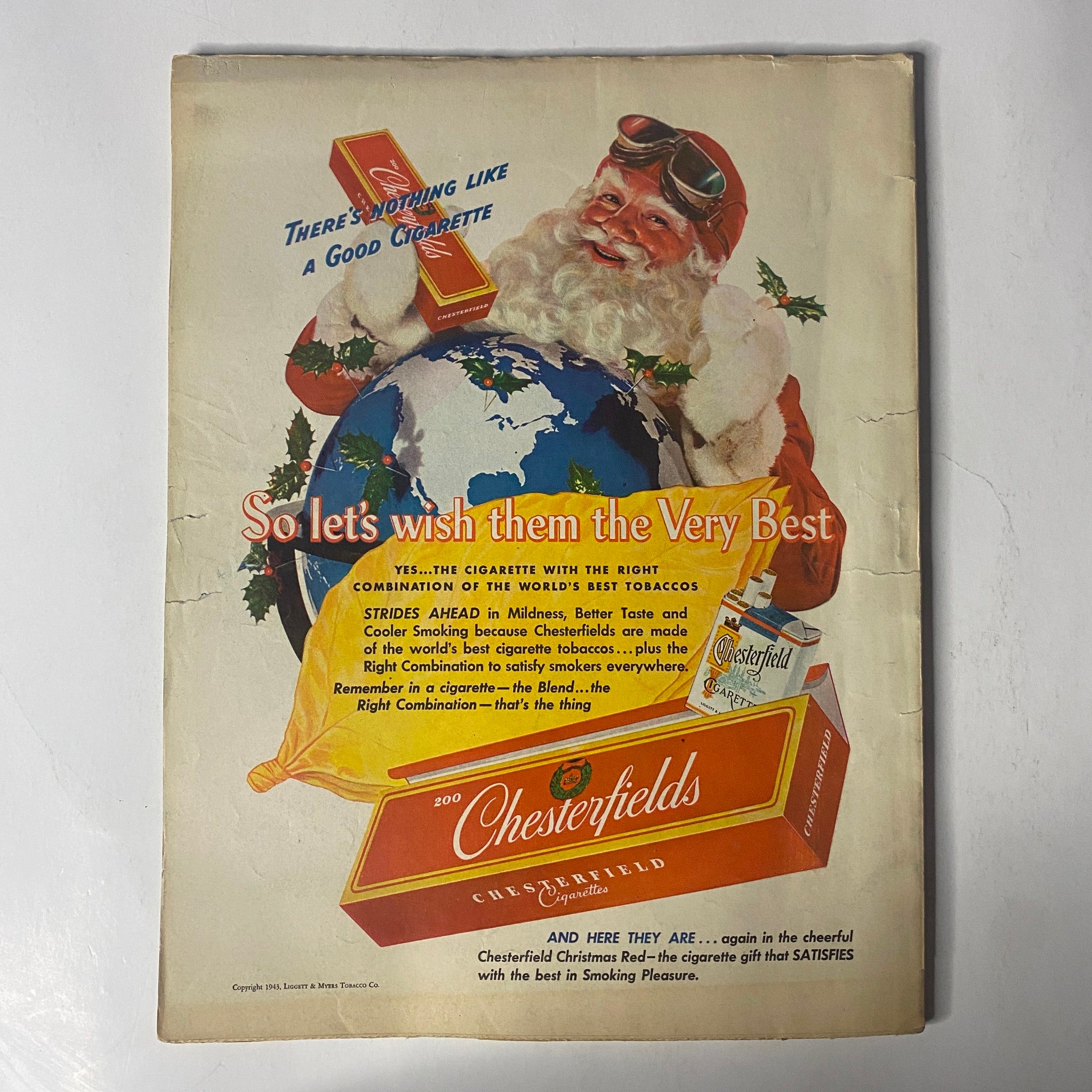 Vintage advertisement for Chesterfield cigarettes featured on the back cover of Radio Mirror Magazine December 1943, showcasing a Santa Claus theme with a globe.