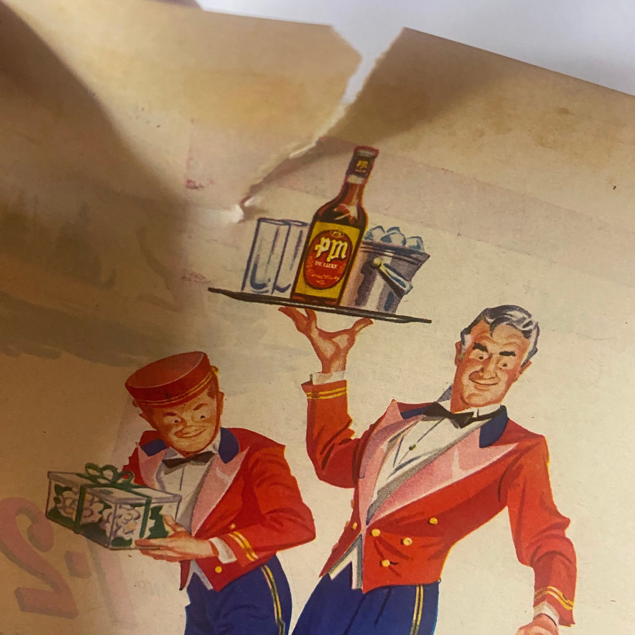 Detailed view of a waiter in a tuxedo showcasing a PM liquor bottle and drinks on a tray, from a vintage advertisement in the Field & Stream Magazine May 1948 titled 'Refuge Payoff' by Harold Titus.
