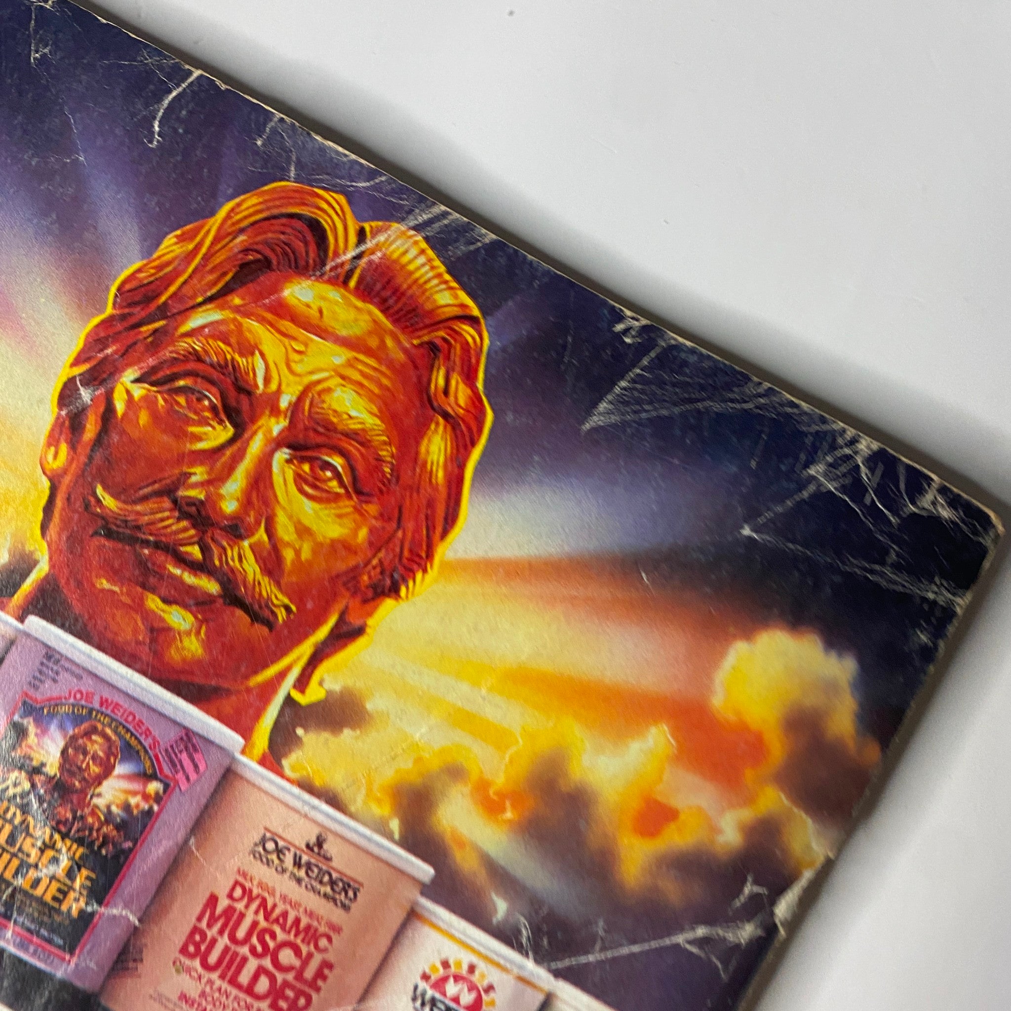 Close-up of the back cover of Muscle & Fitness Magazine July 1984 displaying promotional content and a stylized graphic of Joe Weider.