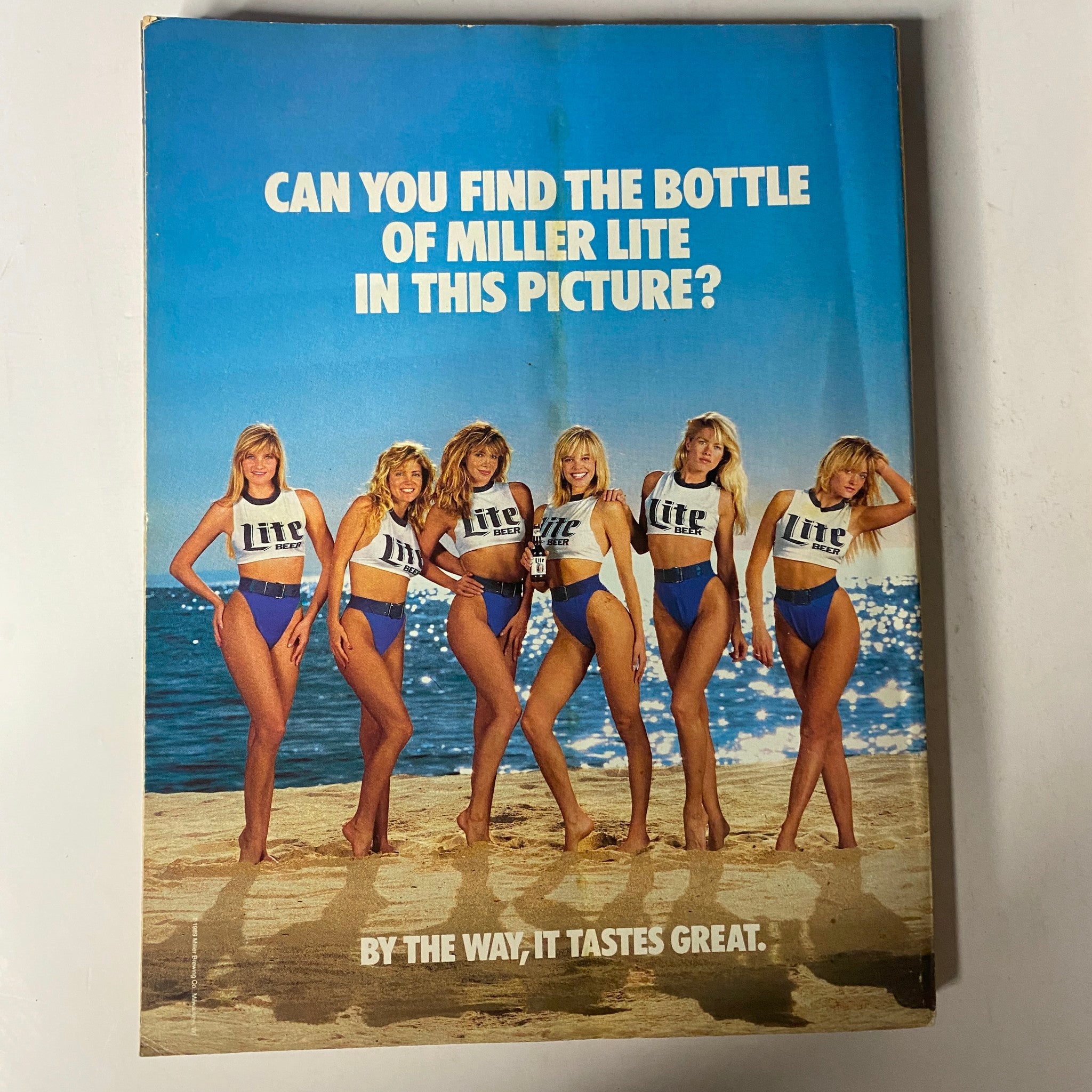 Cover of Muscle & Fitness Magazine May 1989 featuring Scott Wilson and Nora Kozma, showcasing six models in a playful beach setting asking viewers if they can find a bottle of Miller Lite.