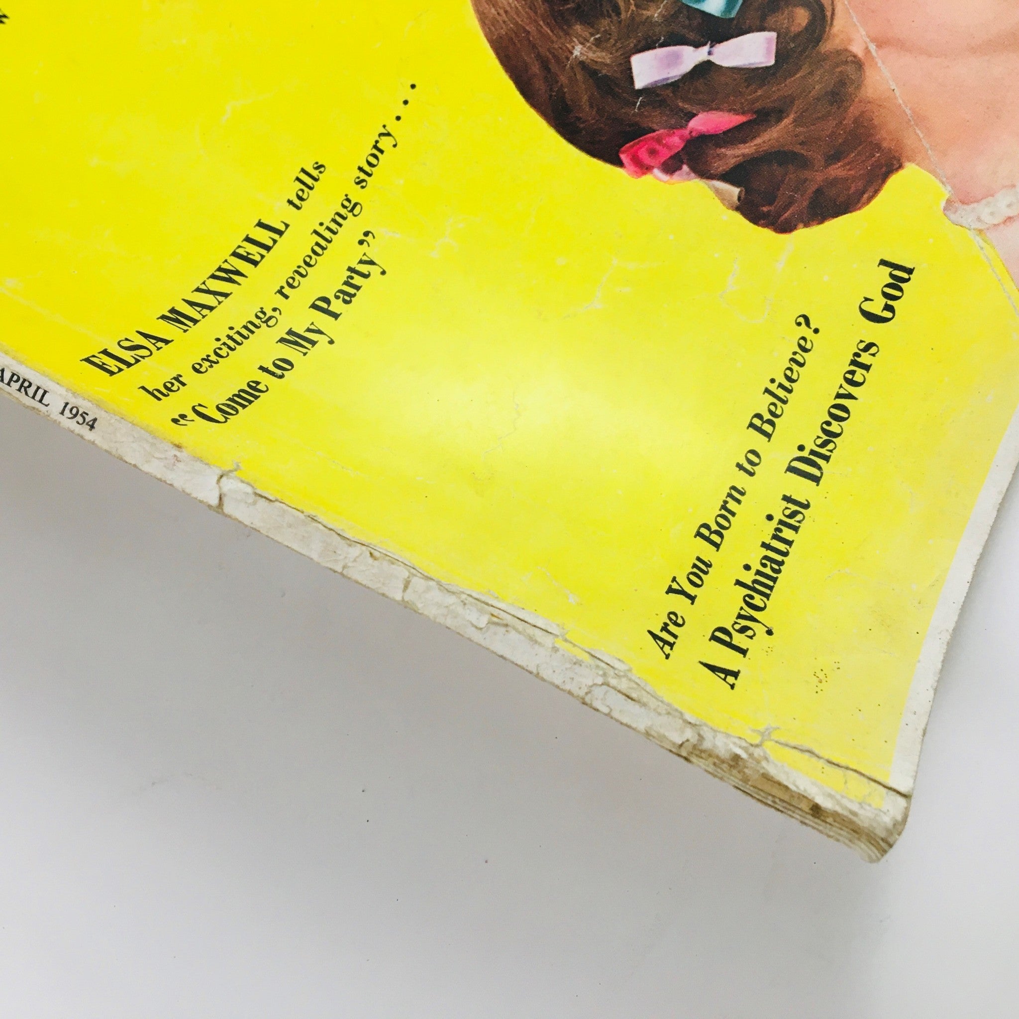 Close-up view of Woman's Home Companion April 1954 cover with an emphasis on the text 'ELSA MAXWELL tells her exciting, revealing story' and the background showcasing a woman with colorful hair accessories.