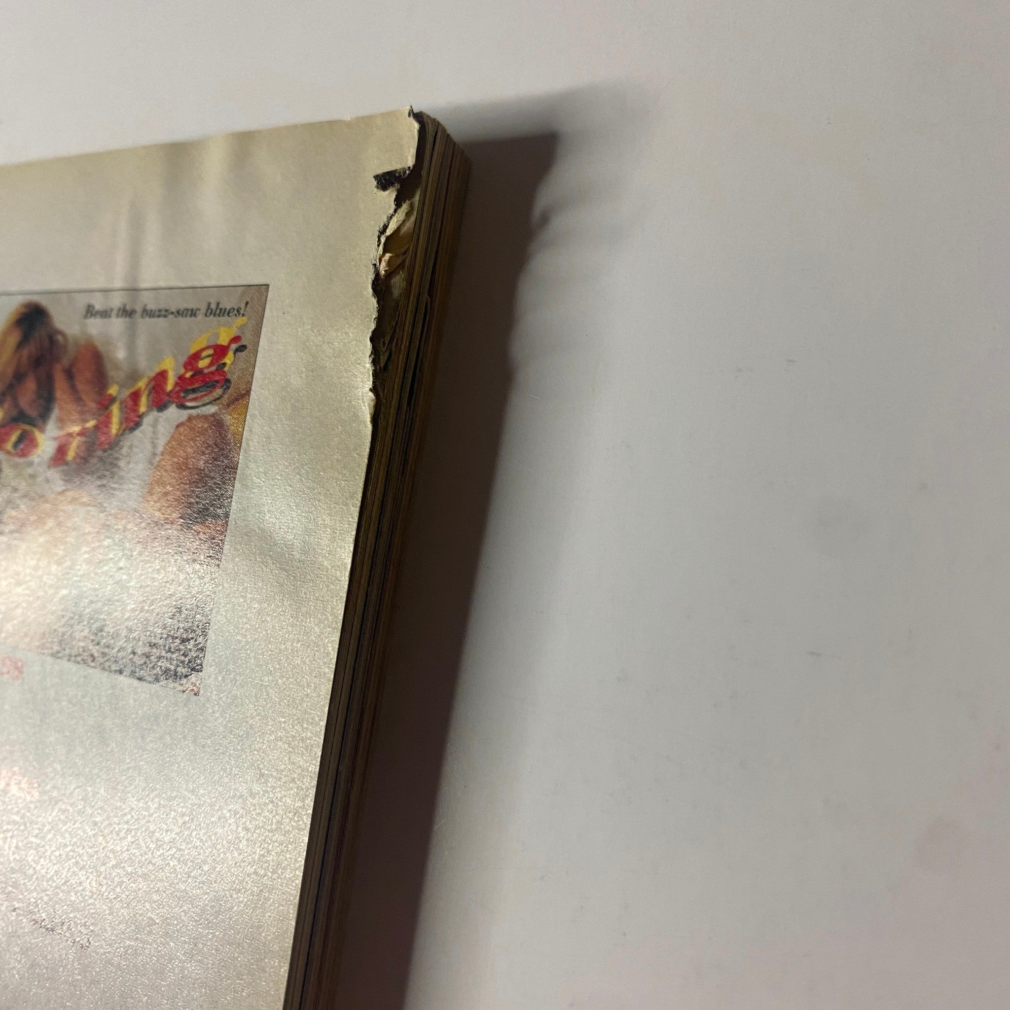 Side view of the June 1995 Muscle & Fitness Magazine, illustrating wear with torn pages, emphasizing its used condition.