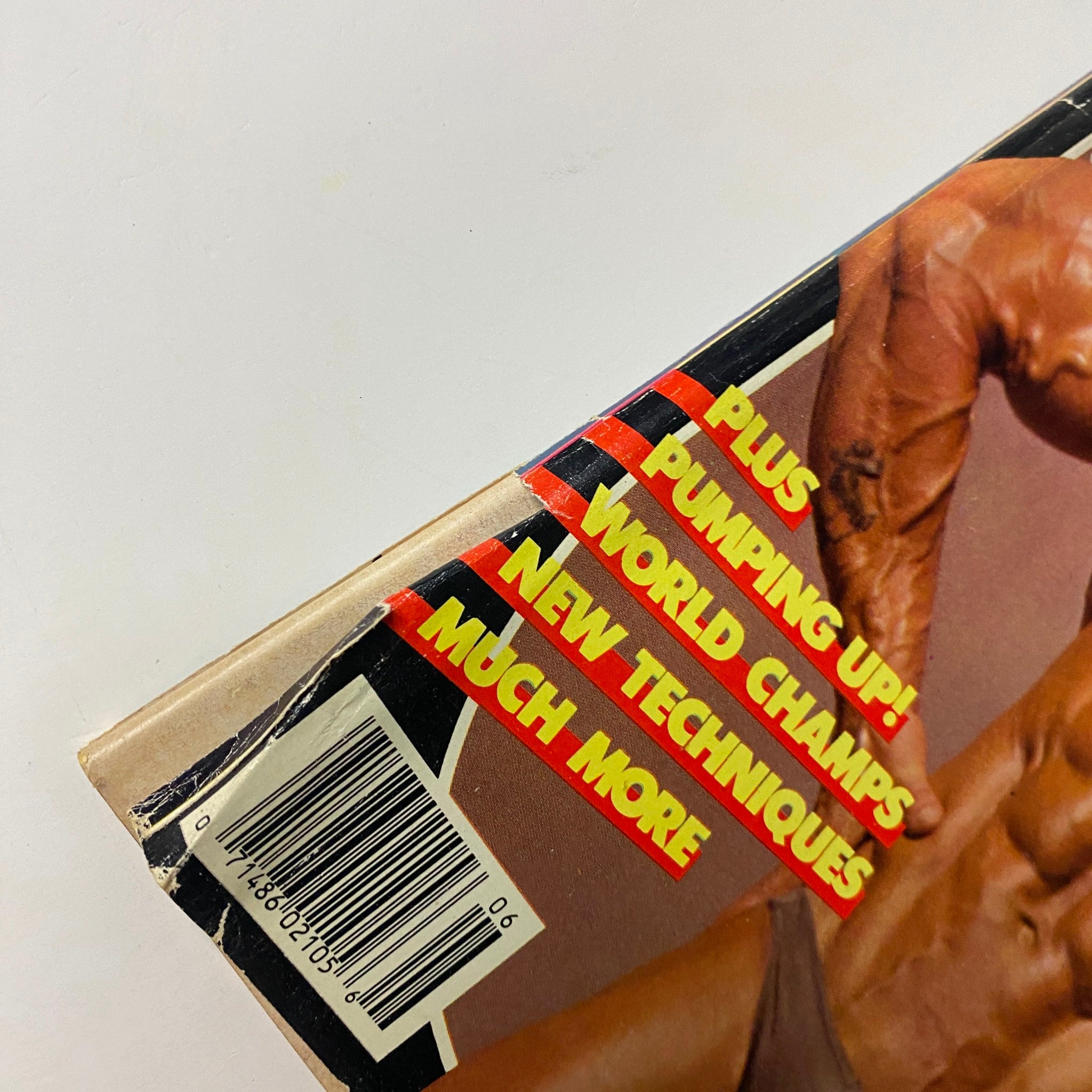 Close-up shot of the spine of MuscleMag International Magazine June 1986, highlighting the text 'PLUS PUMPING UP! WORLD CHAMP'S NEW TECHNIQUES MUCH MORE' for bodybuilding enthusiasts.