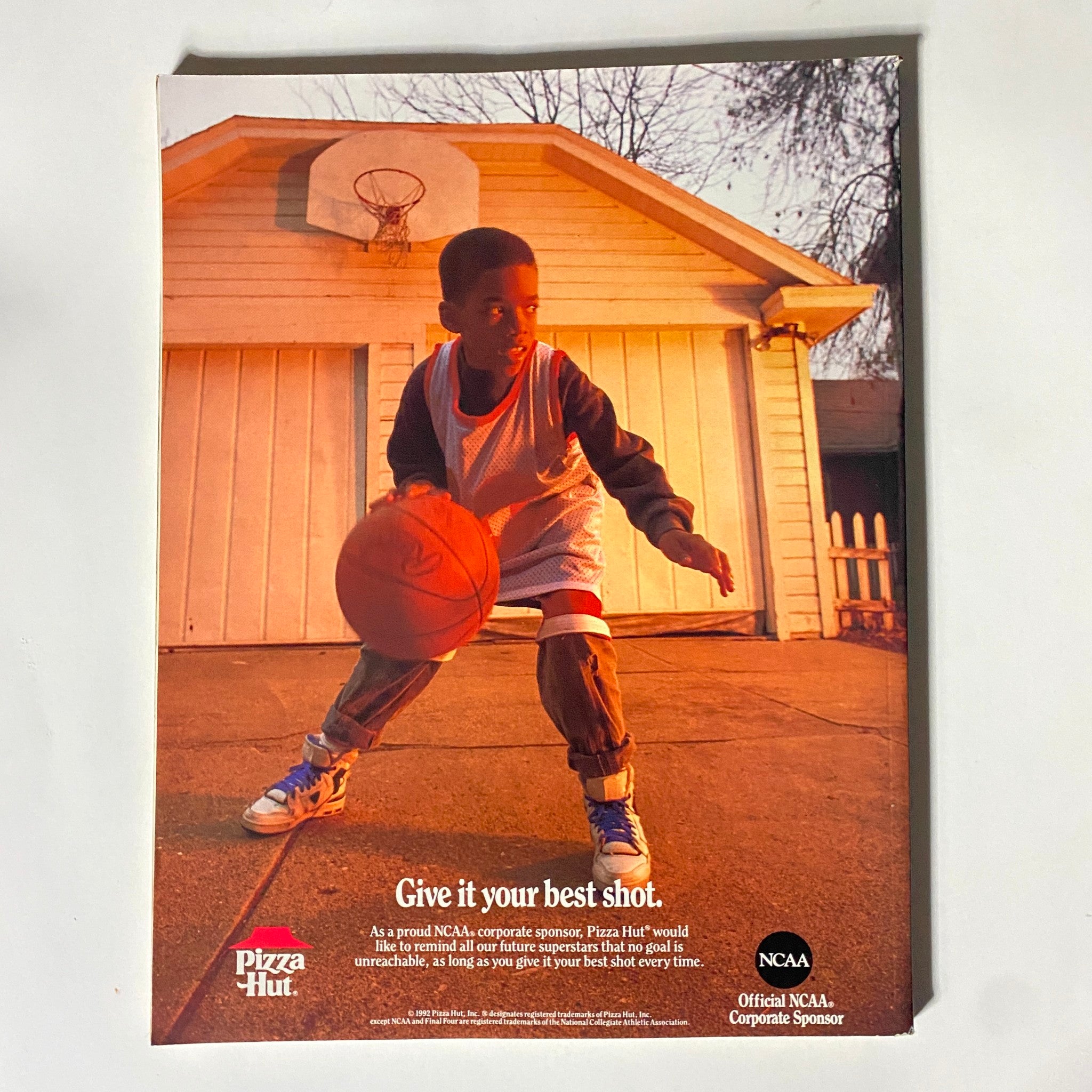 Pizza Hut advertisement from the NCAA Basketball Preview Magazine 1992-1993, promoting encouragement for young basketball players with the tagline 'Give it your best shot'.