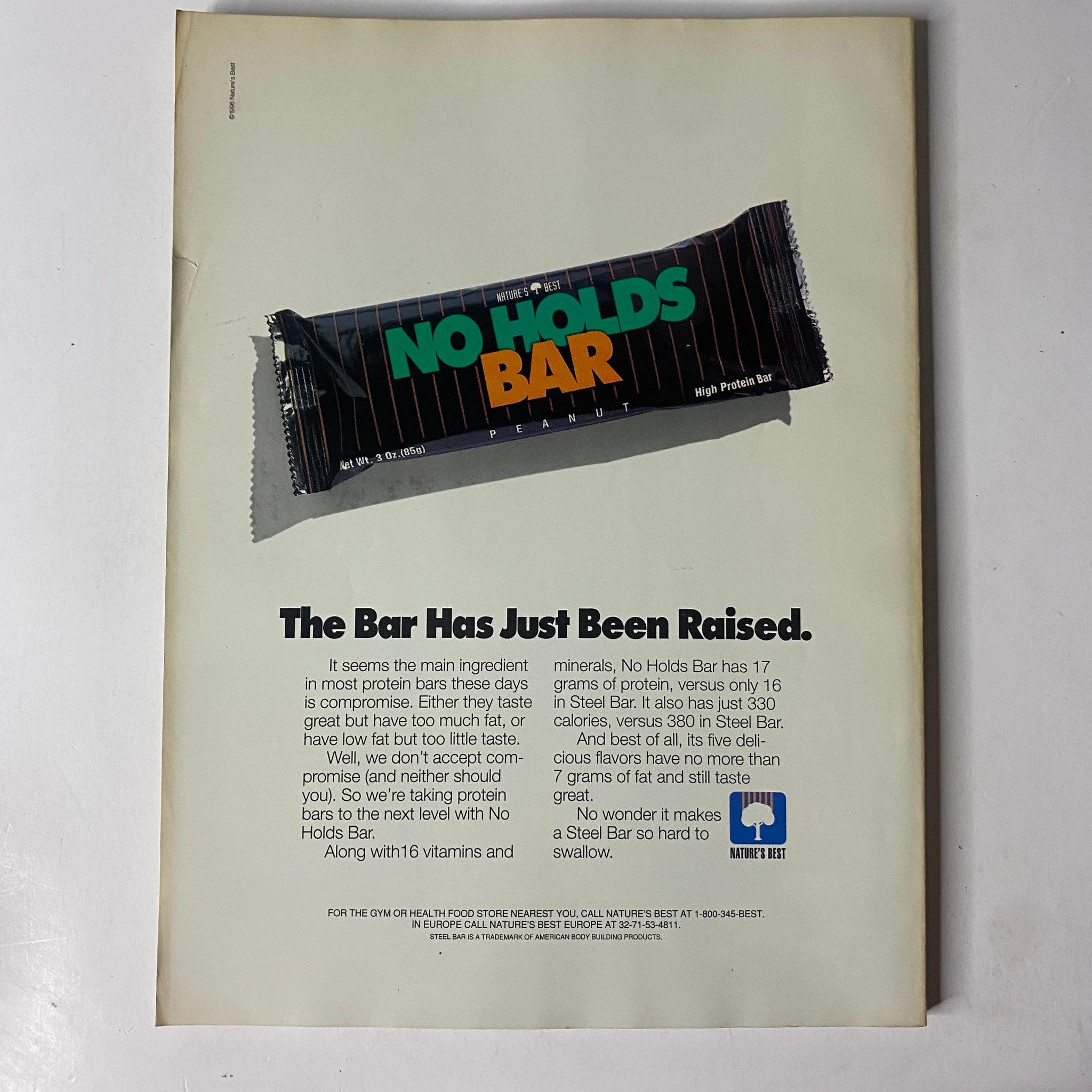 Vintage advertisement featuring 'No Holds Bar' protein bar, claiming to have 17 grams of protein per serving and a rich nutritional profile. The ad emphasizes the bar's enhancement of health and fitness, accompanied by the title 'MuscleMag International Magazine June 1996 Mike O'Hearn, Christi Walker VG.'