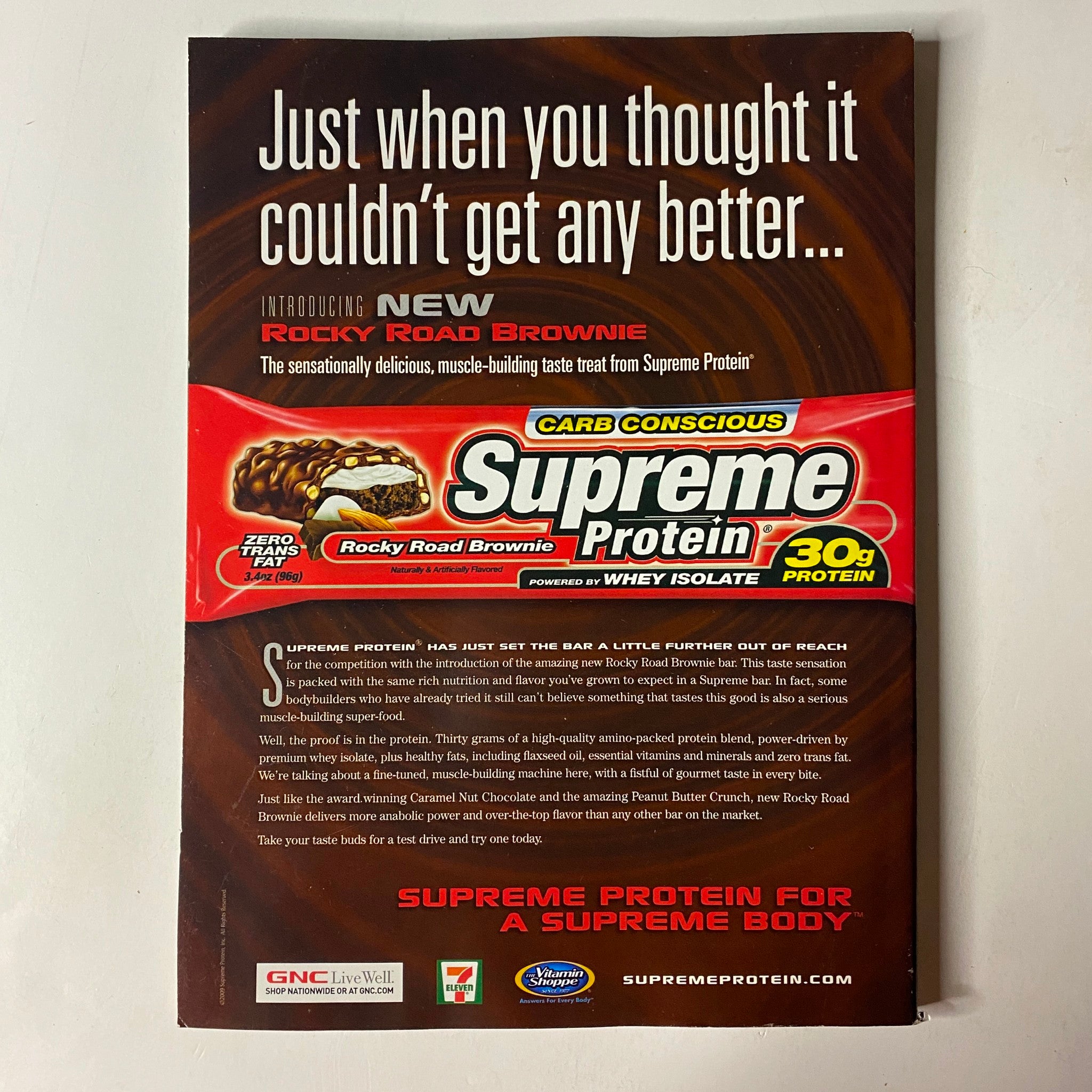 Advertisement for Supreme Protein Rocky Road Brownie featured in MuscleMag International Magazine, November 2009, No. 330, promoting a high-protein snack option for fitness enthusiasts.
