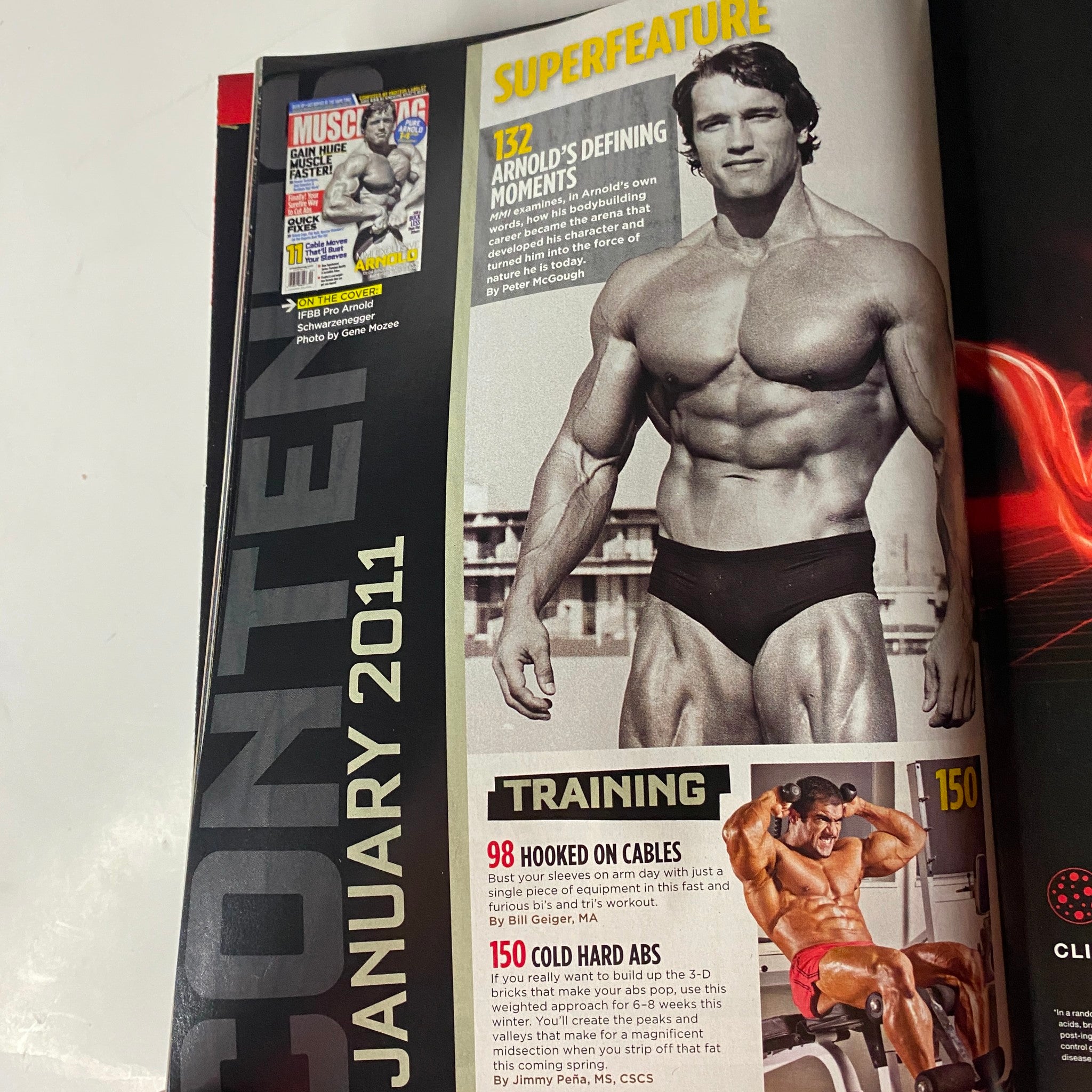 Interior page of MuscleMag International Magazine January 2011 No. 344 highlighting Arnold Schwarzenegger's defining moments in bodybuilding, including training tips and featured workouts.