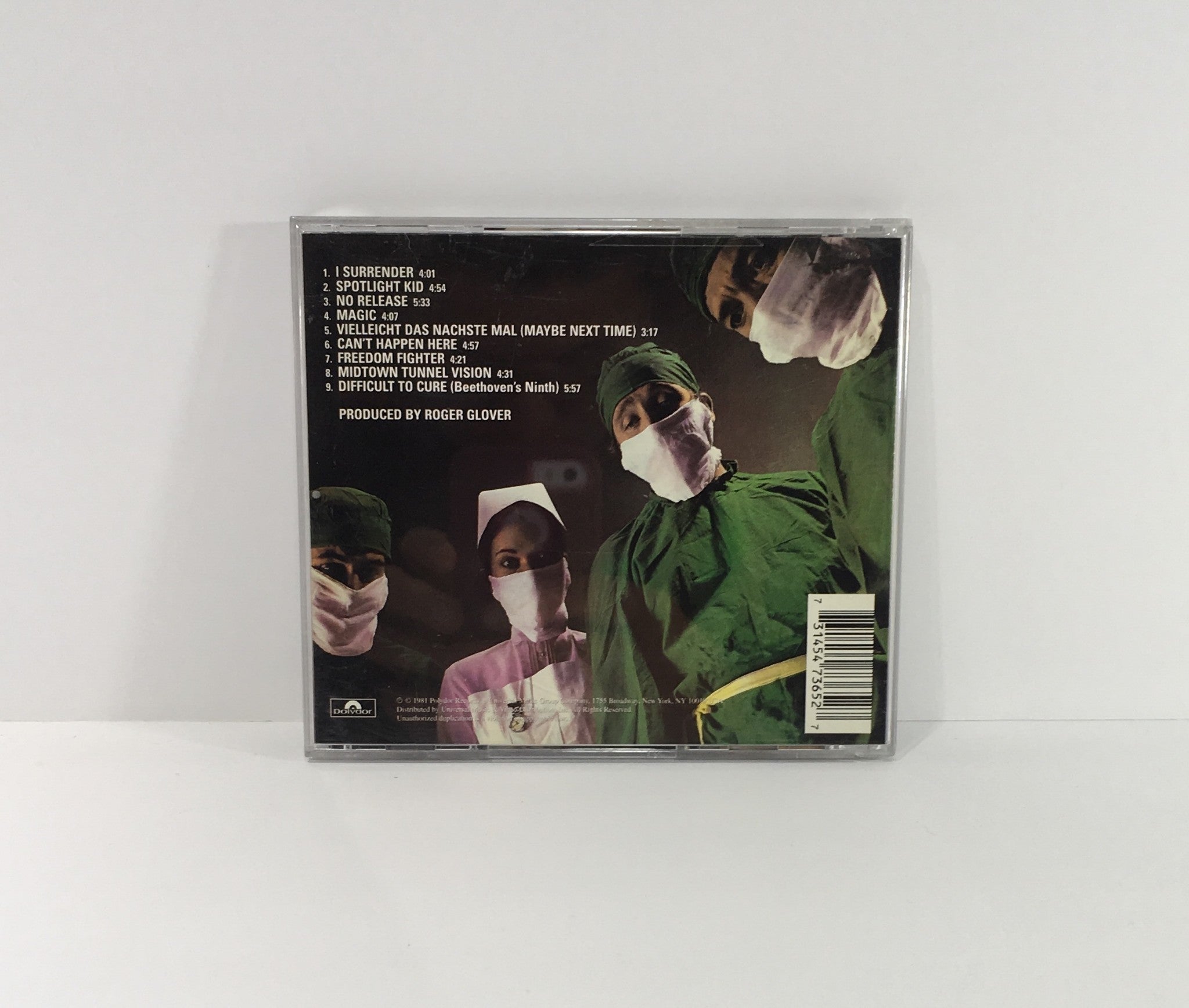 Back cover of the Rainbow Difficult To Cure Remasters Music Audio CD featuring tracklist and band members in surgical masks.