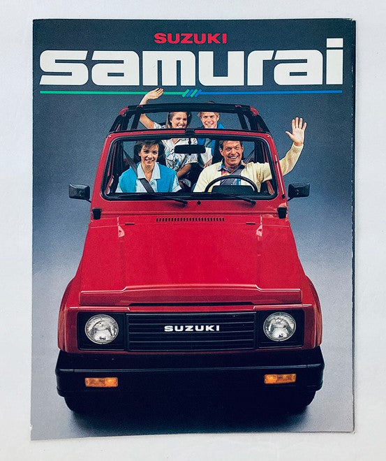 Cover of the 1986 Suzuki Samurai Car Dealer Showroom Sales Brochure Guide Catalog featuring a bright red Suzuki Samurai vehicle with four people smiling and waving from the front seat, highlighting the fun and adventure associated with this compact SUV.